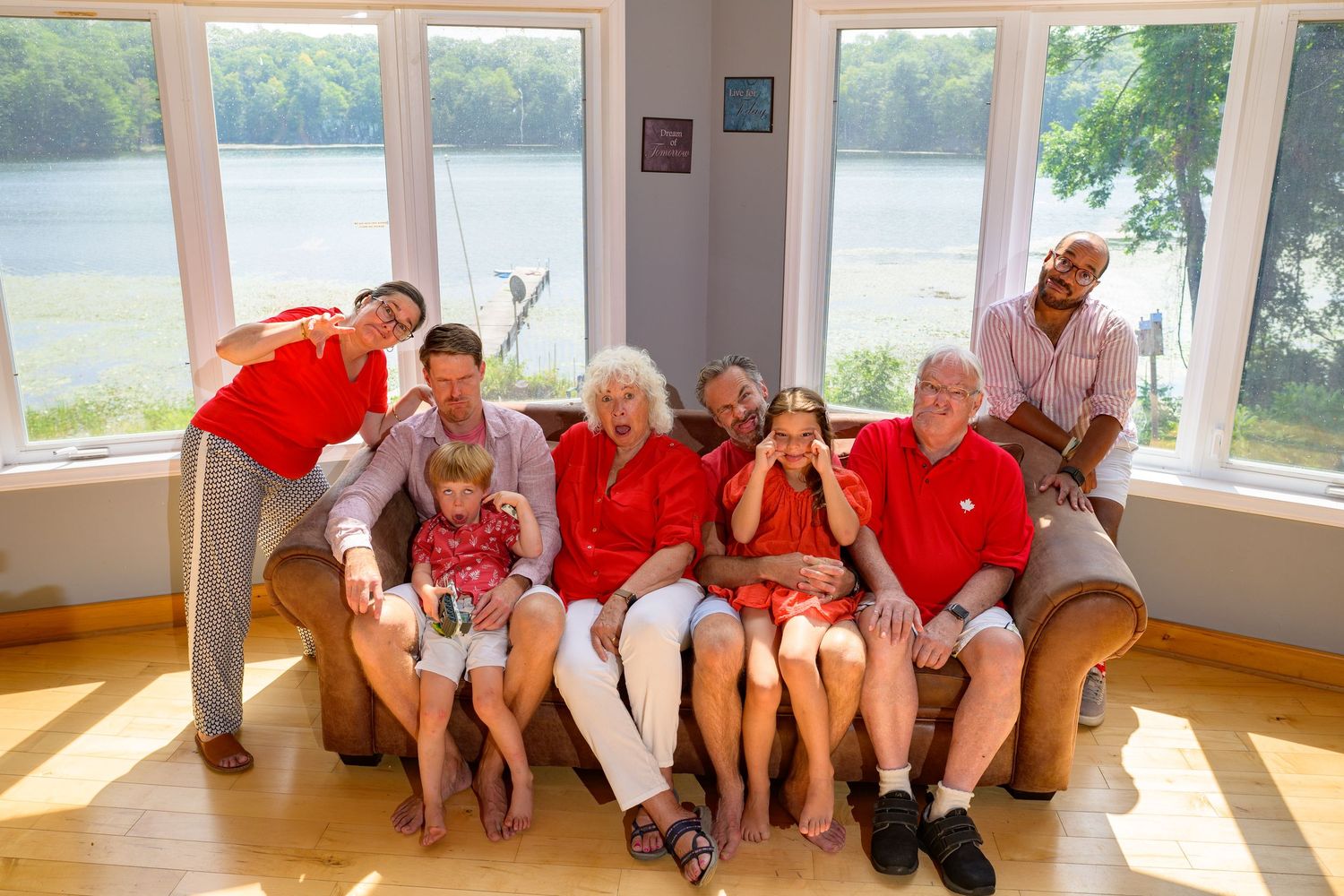 Group of seniors sitting on benches in a bright sunlit room by large windows during a social activity.