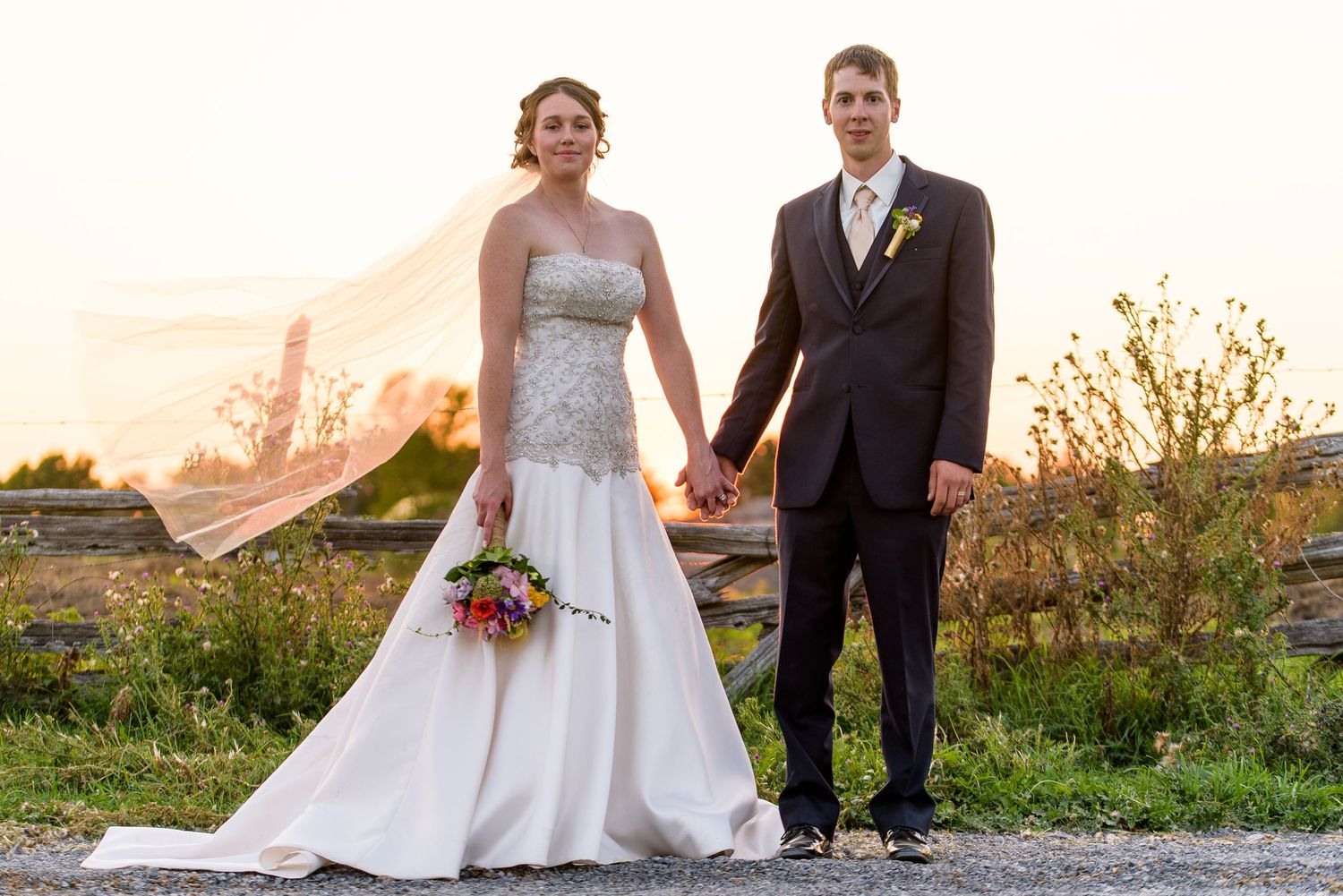 Wedding couple poses together during golden hour sunset in a garden setting.