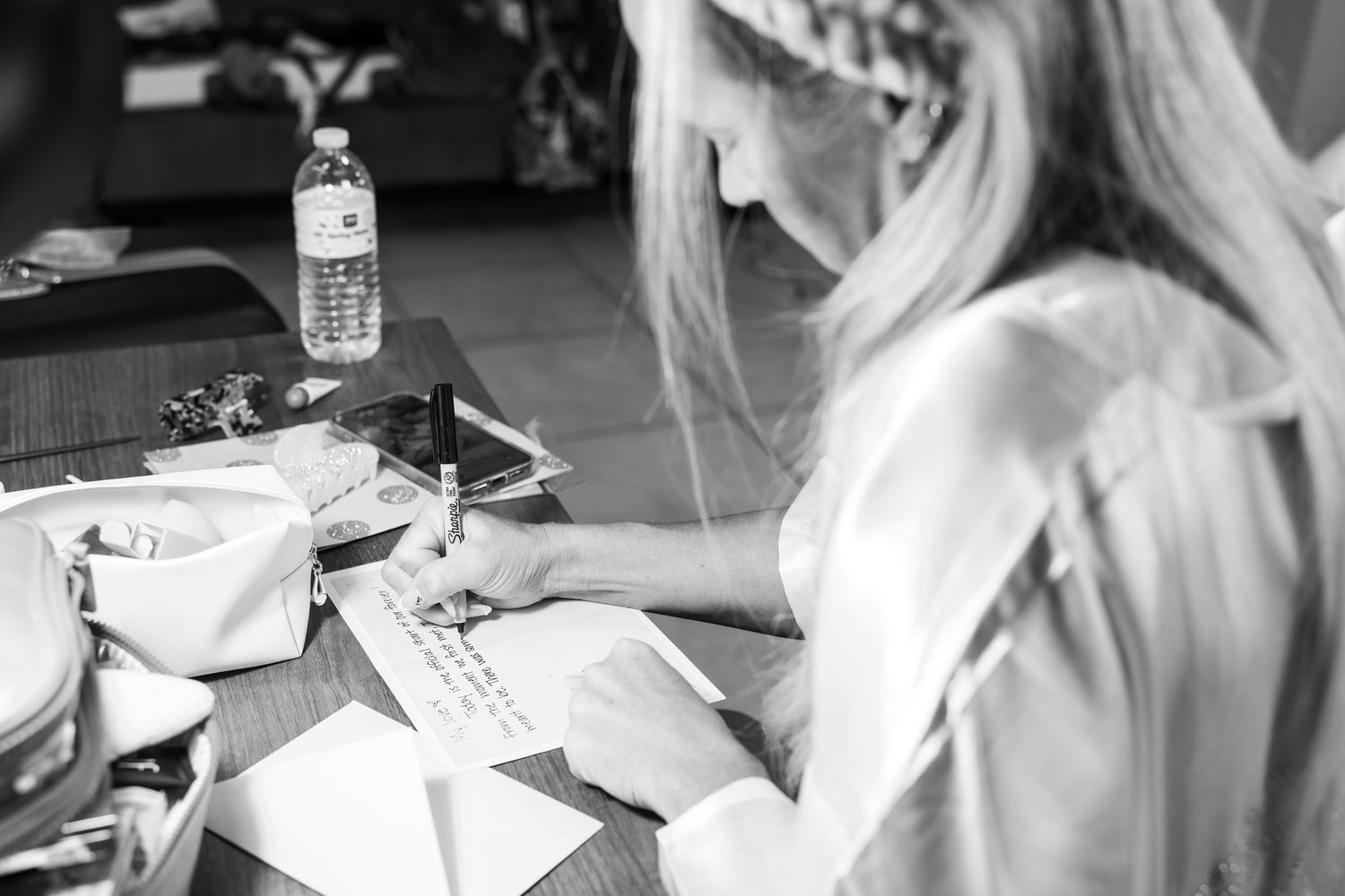 Wedding preparation scene with writing and paperwork on a table.