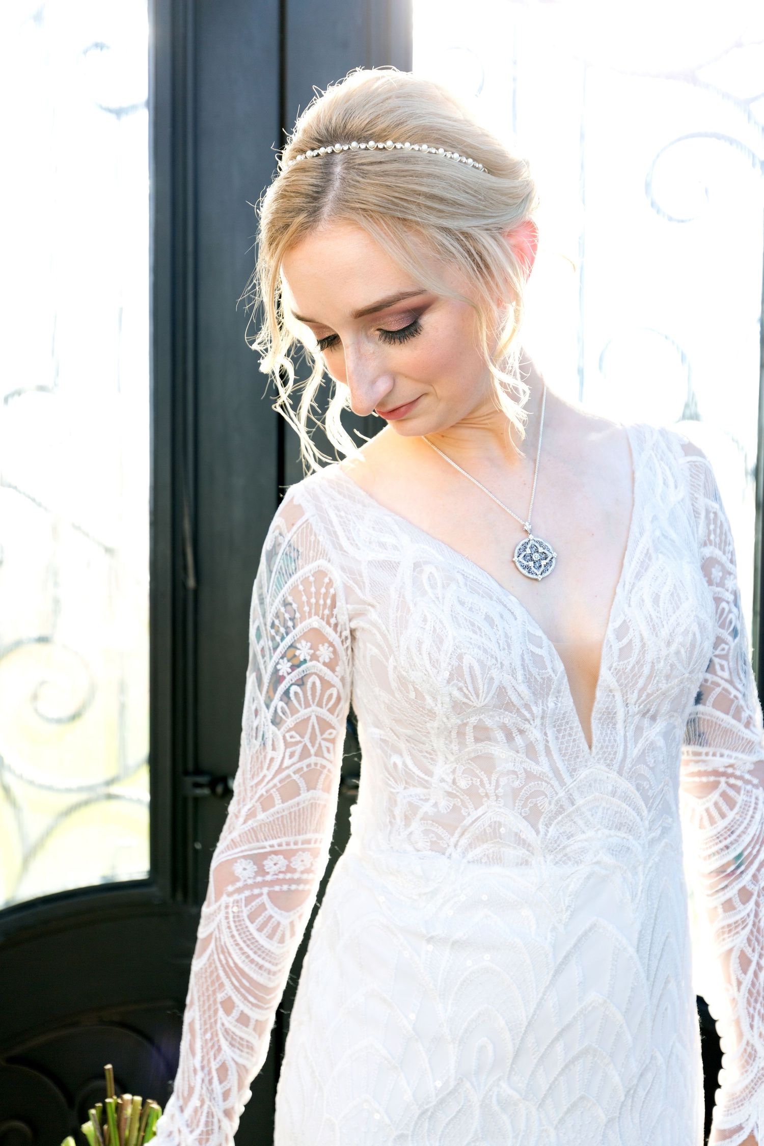 Close-up detail of delicate white lace sleeves on an elegant wedding dress in natural window light.