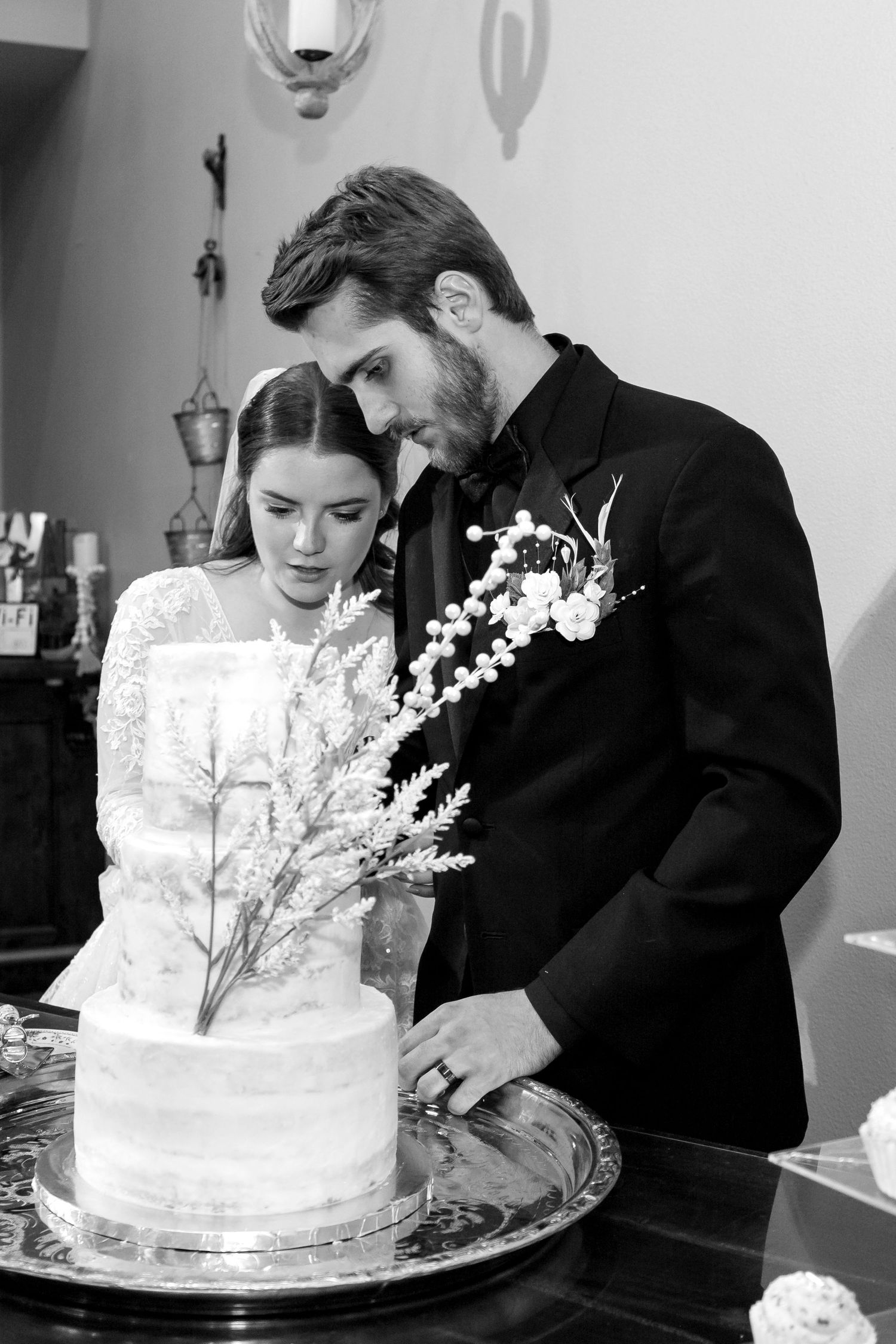 Wedding couple cutting their elegant white tiered cake together at reception.