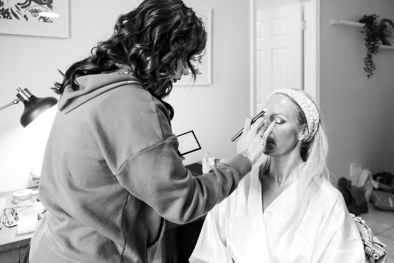 Wedding day preparation showing hair and makeup styling in black and white.