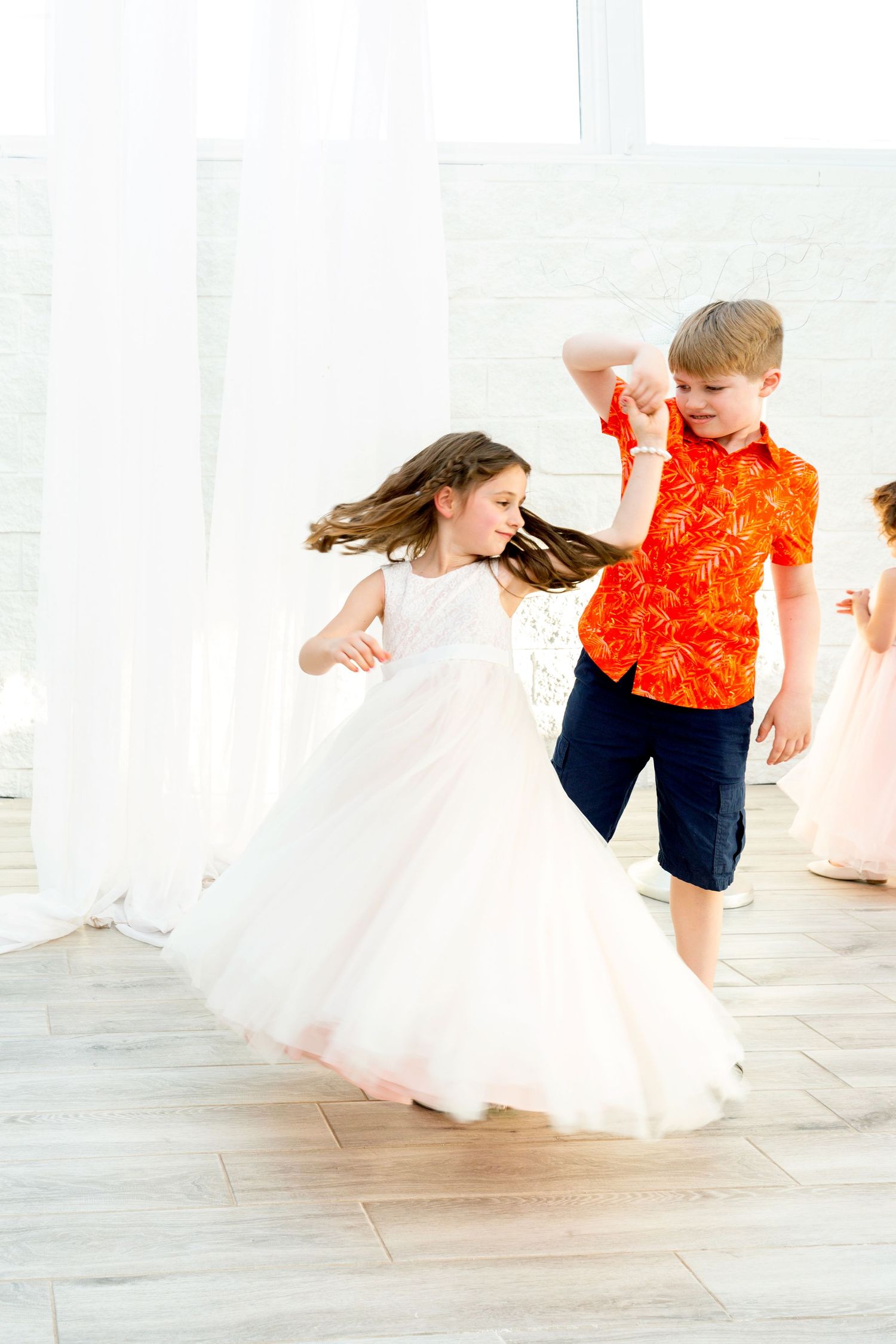 Dynamic dance moves captured during wedding reception in bright white venue.