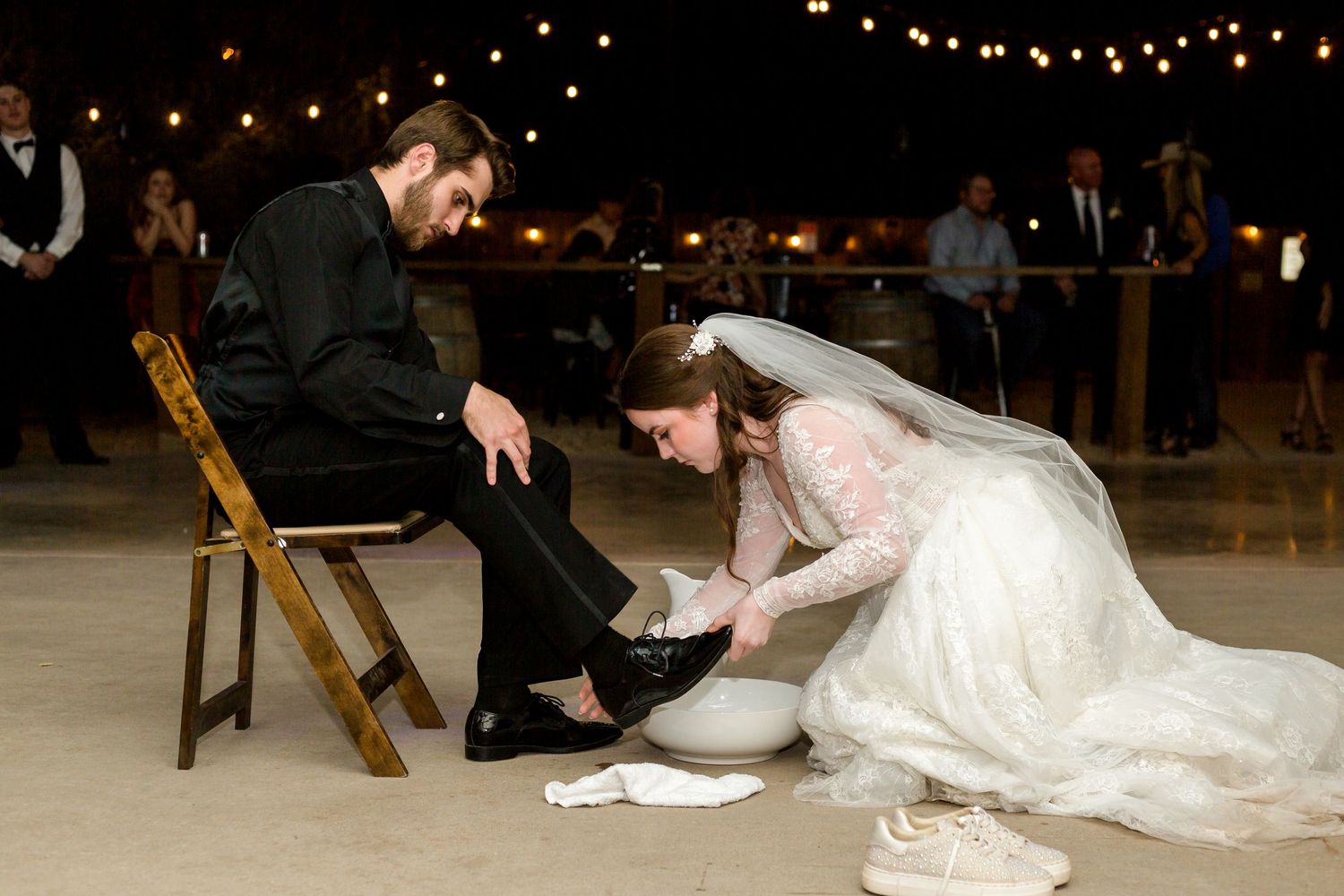 A romantic dance dip captured under twinkling string lights at an outdoor wedding reception.