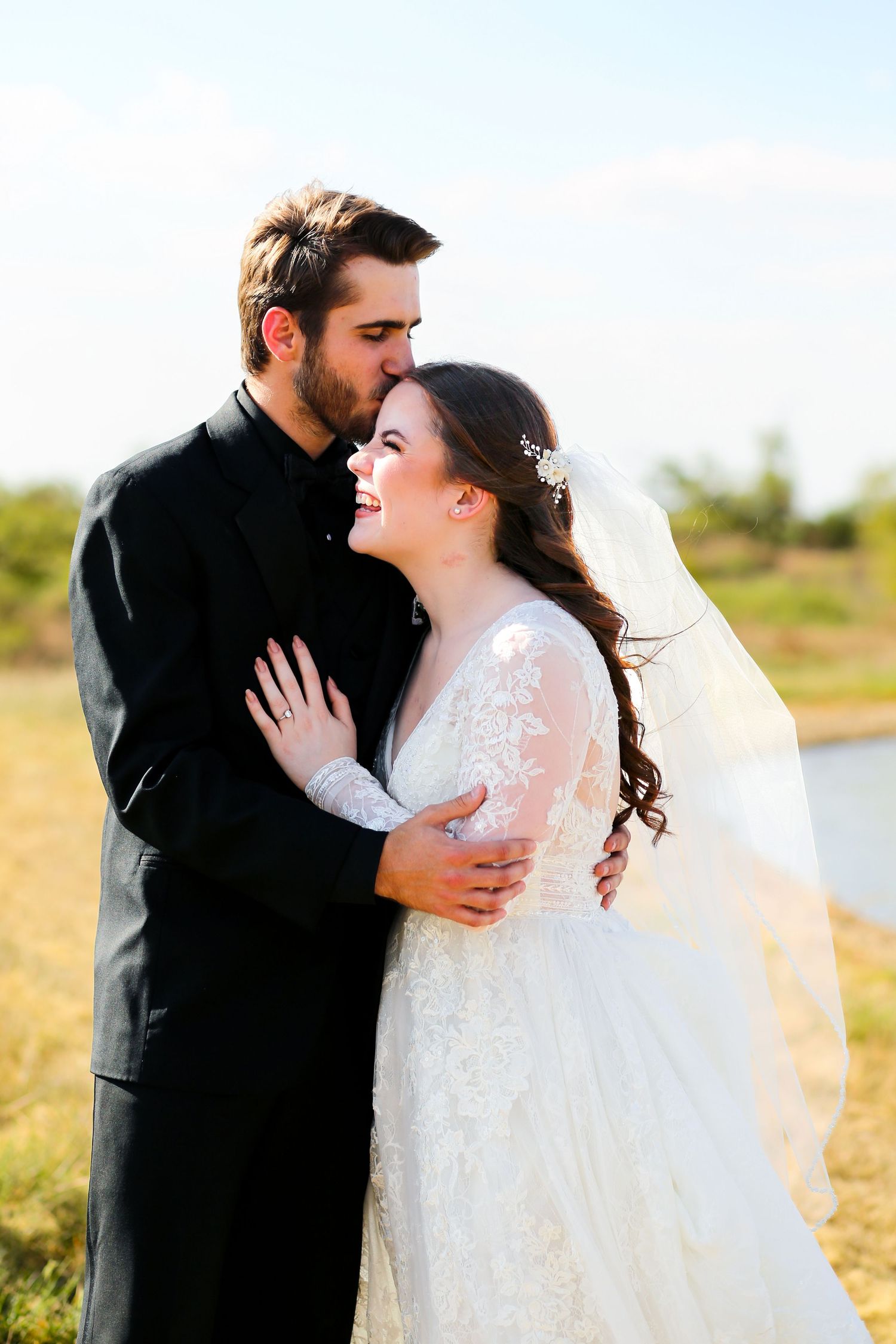 A romantic outdoor wedding portrait captured against a natural landscape.