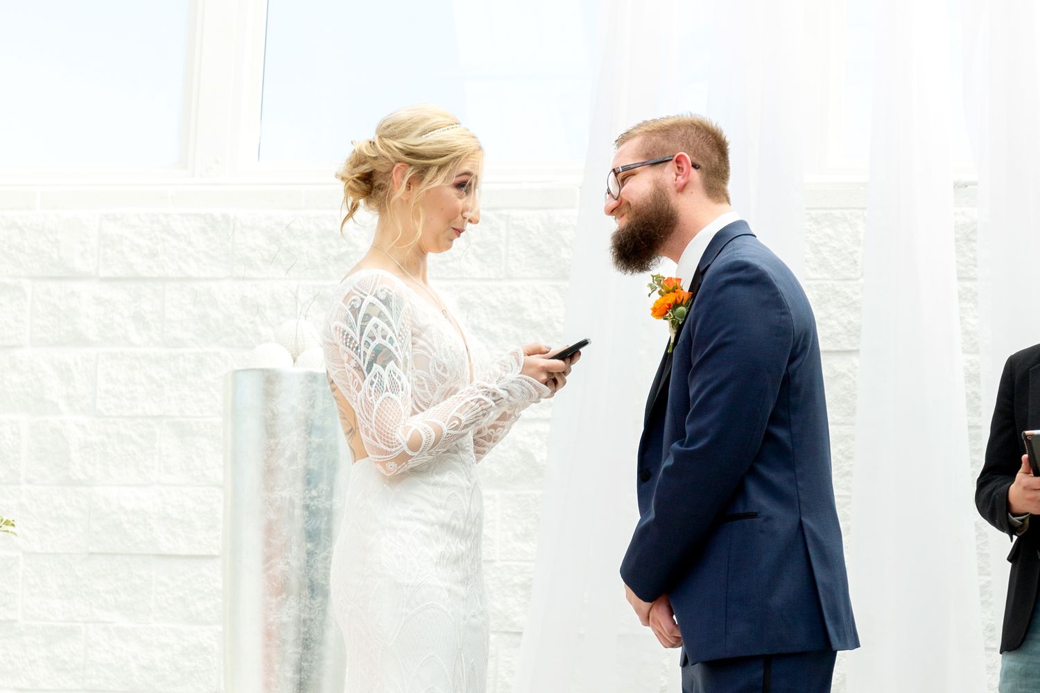 Couple exchanges vows in bright white ceremony space with modern decor.