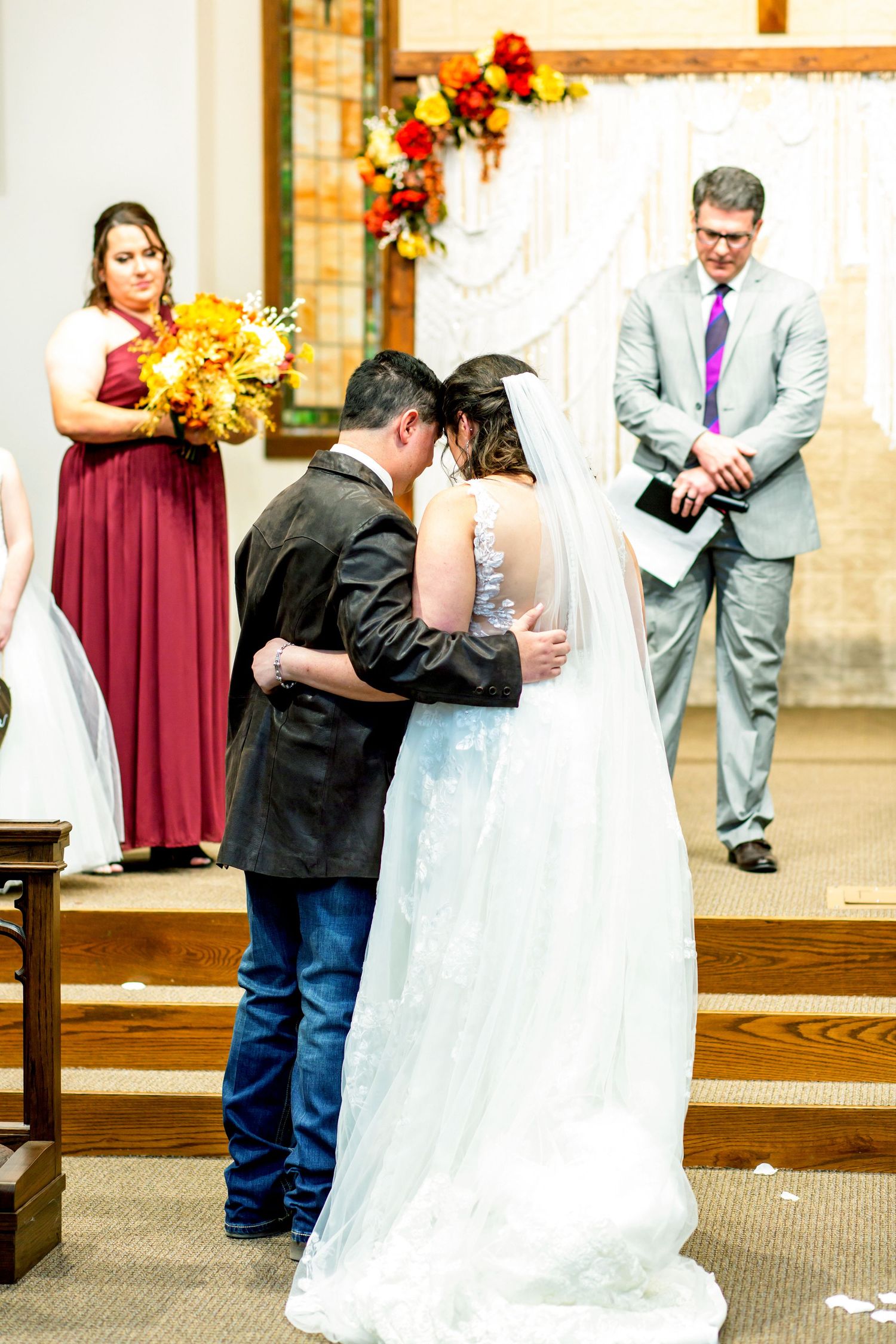 Wedding ceremony moments captured in a church with burgundy and floral decorations.