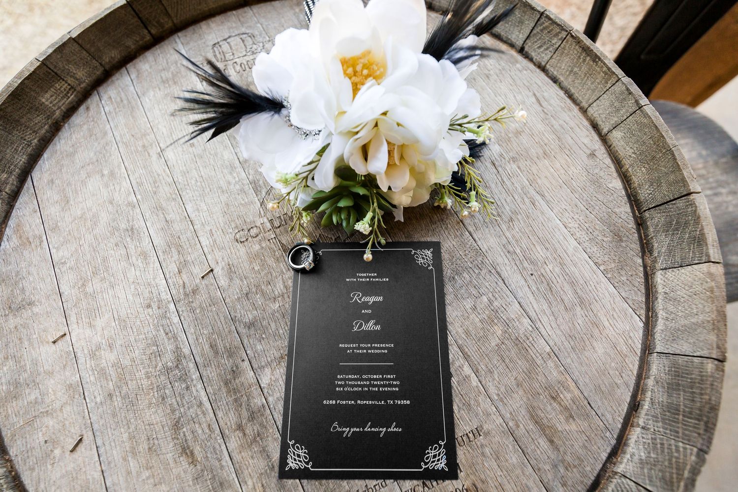 Wedding stationery and white floral arrangements displayed on rustic wood surface.
