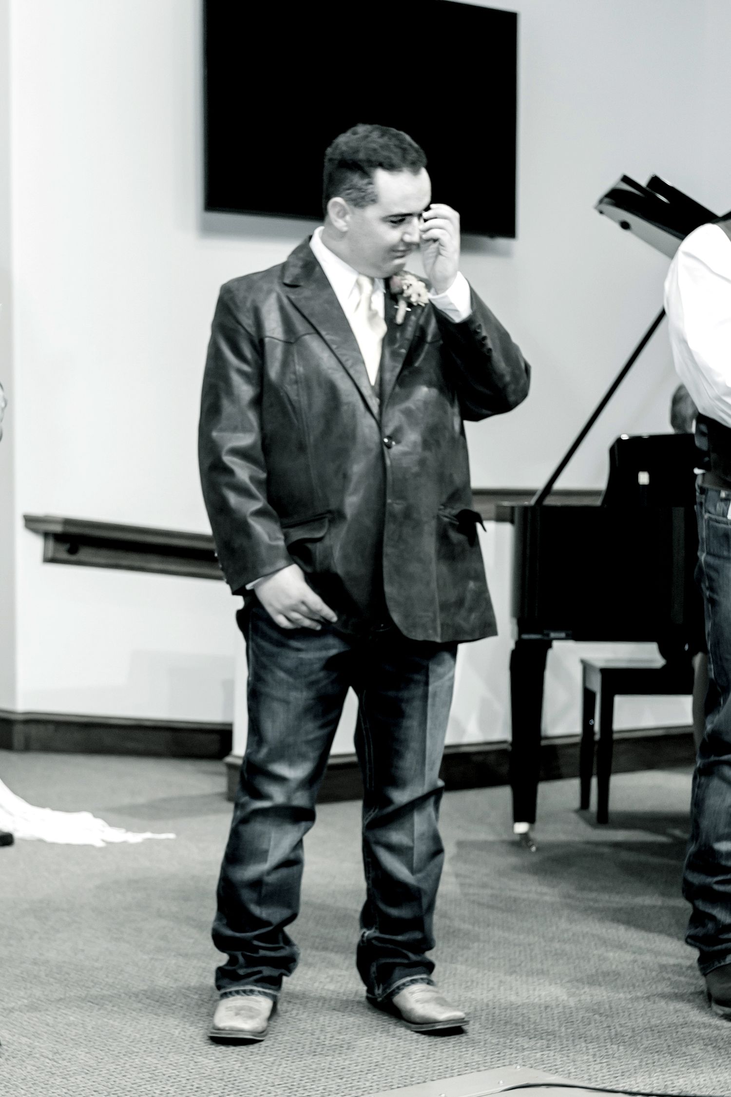 Black and white photo of a small ring bearer in an oversized suit at a wedding.