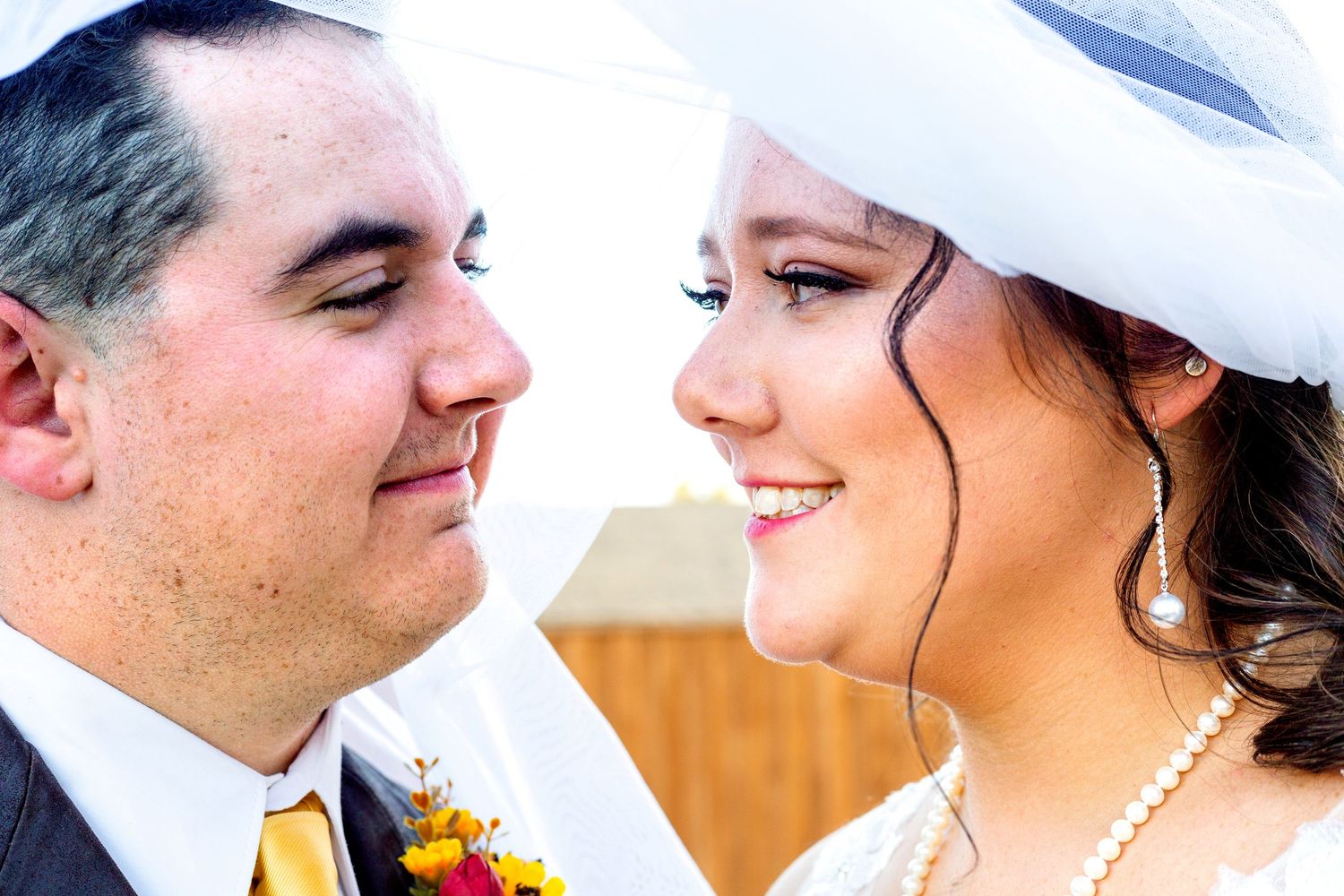 Close-up wedding portrait showing tender moment between couple with yellow boutonniere.