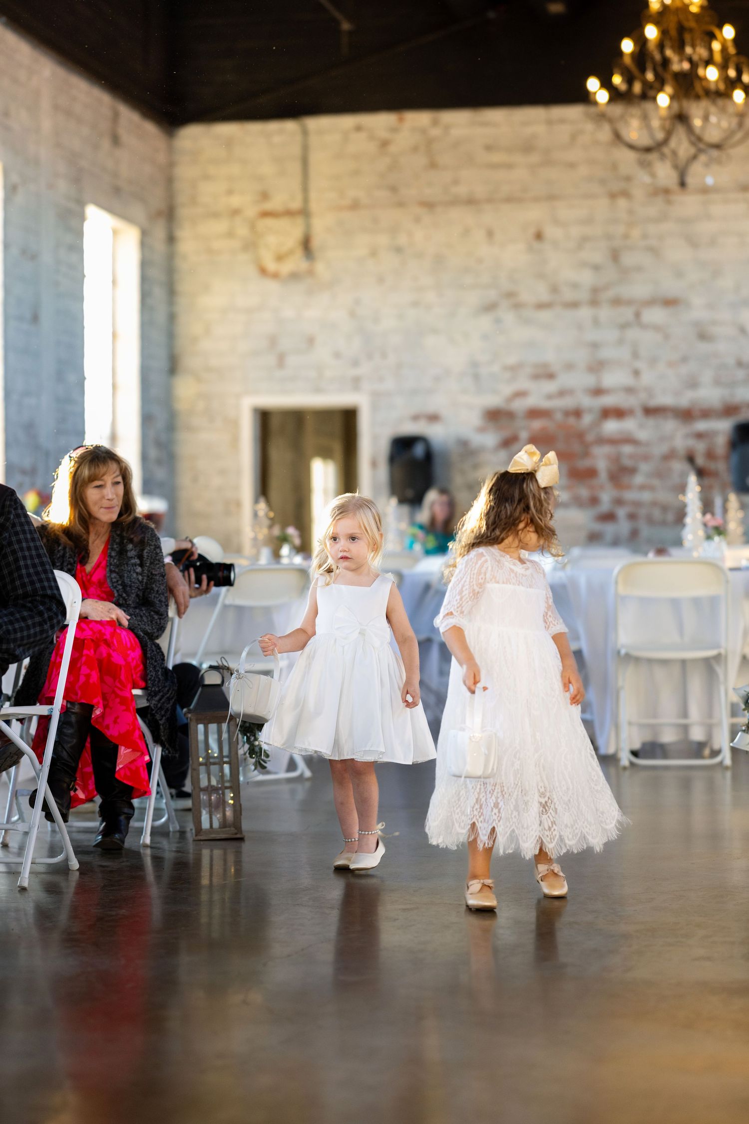 Young flower girls in white dresses dancing at a wedding reception.