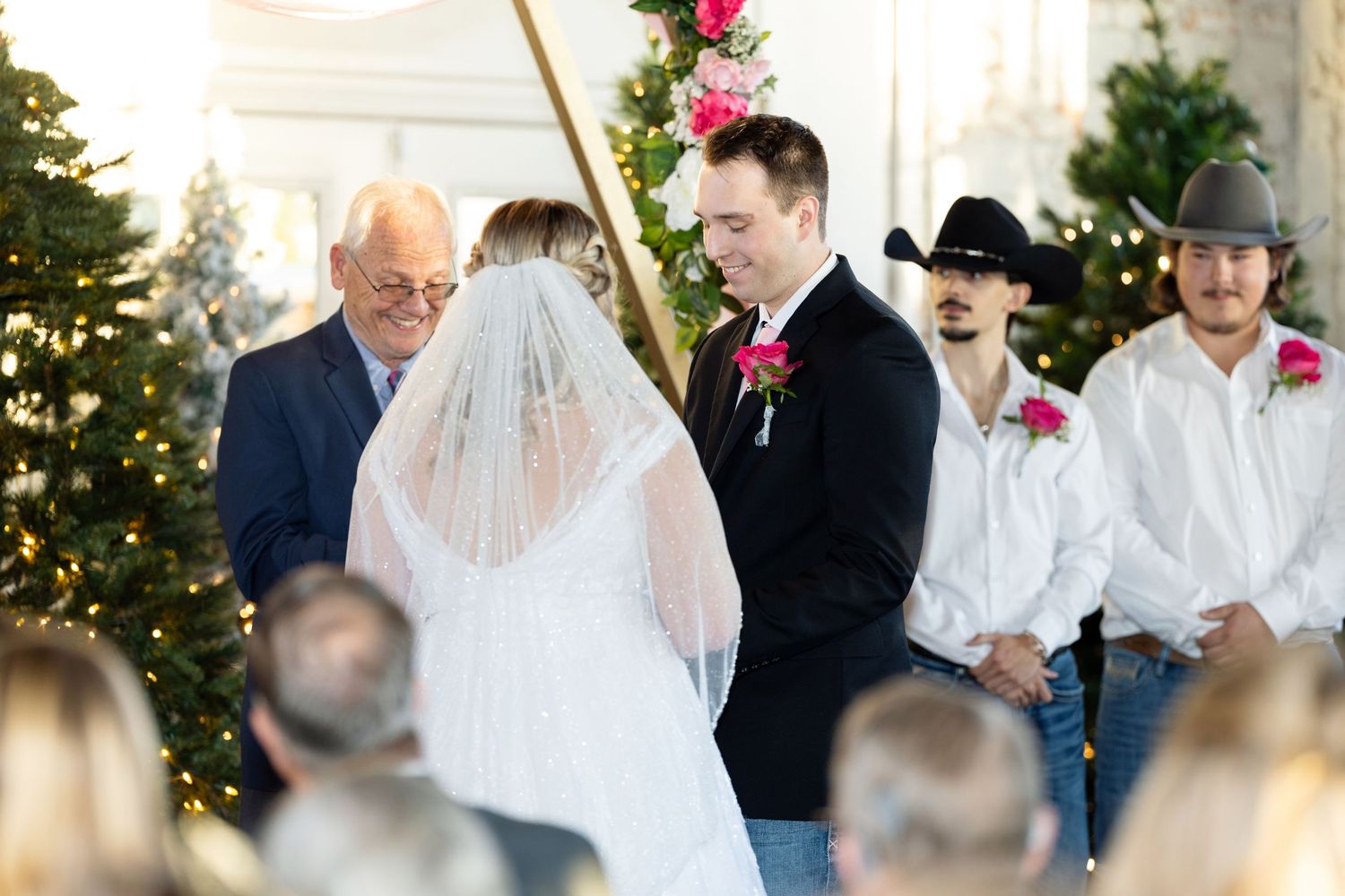 Wedding ceremony setup with decorated trees and chairs in an elegant indoor space.