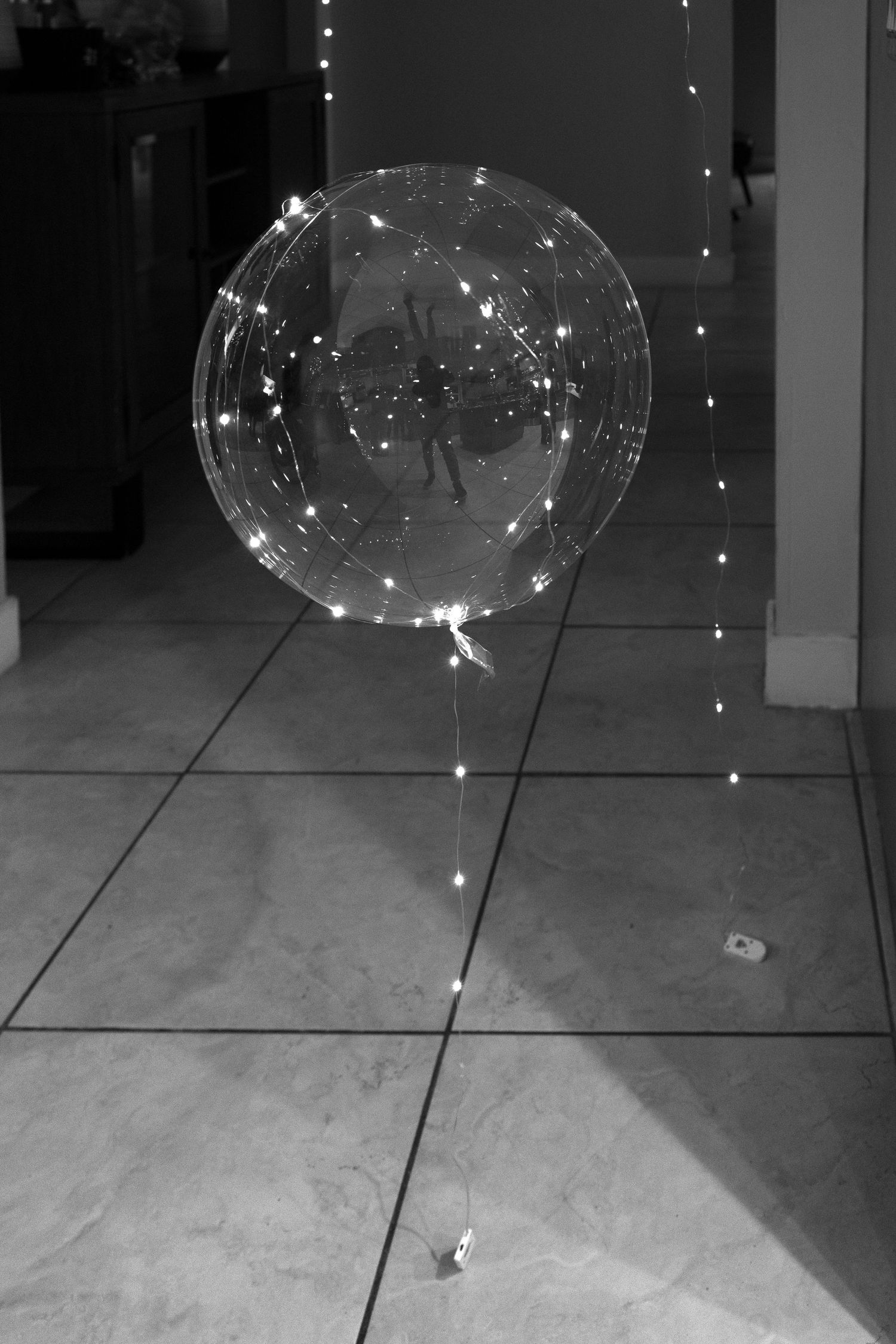 LED string lights create glowing orbs in a dark room.