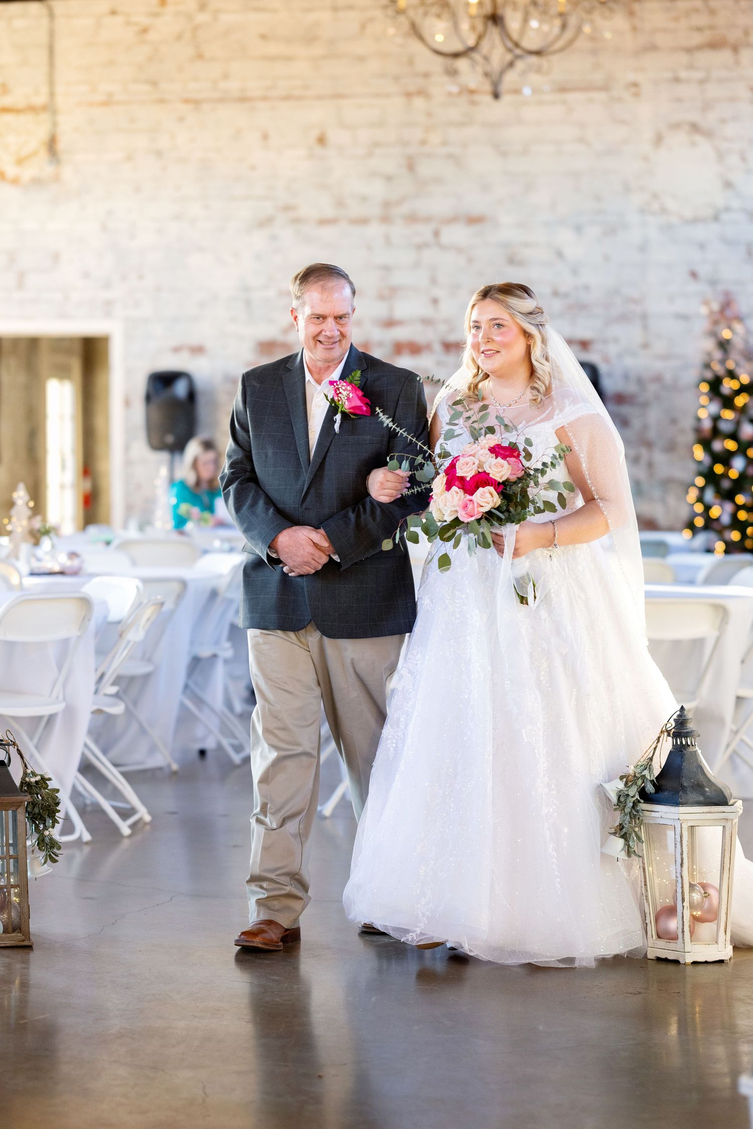Wedding processional in rustic venue with lantern decorations and exposed brick walls.