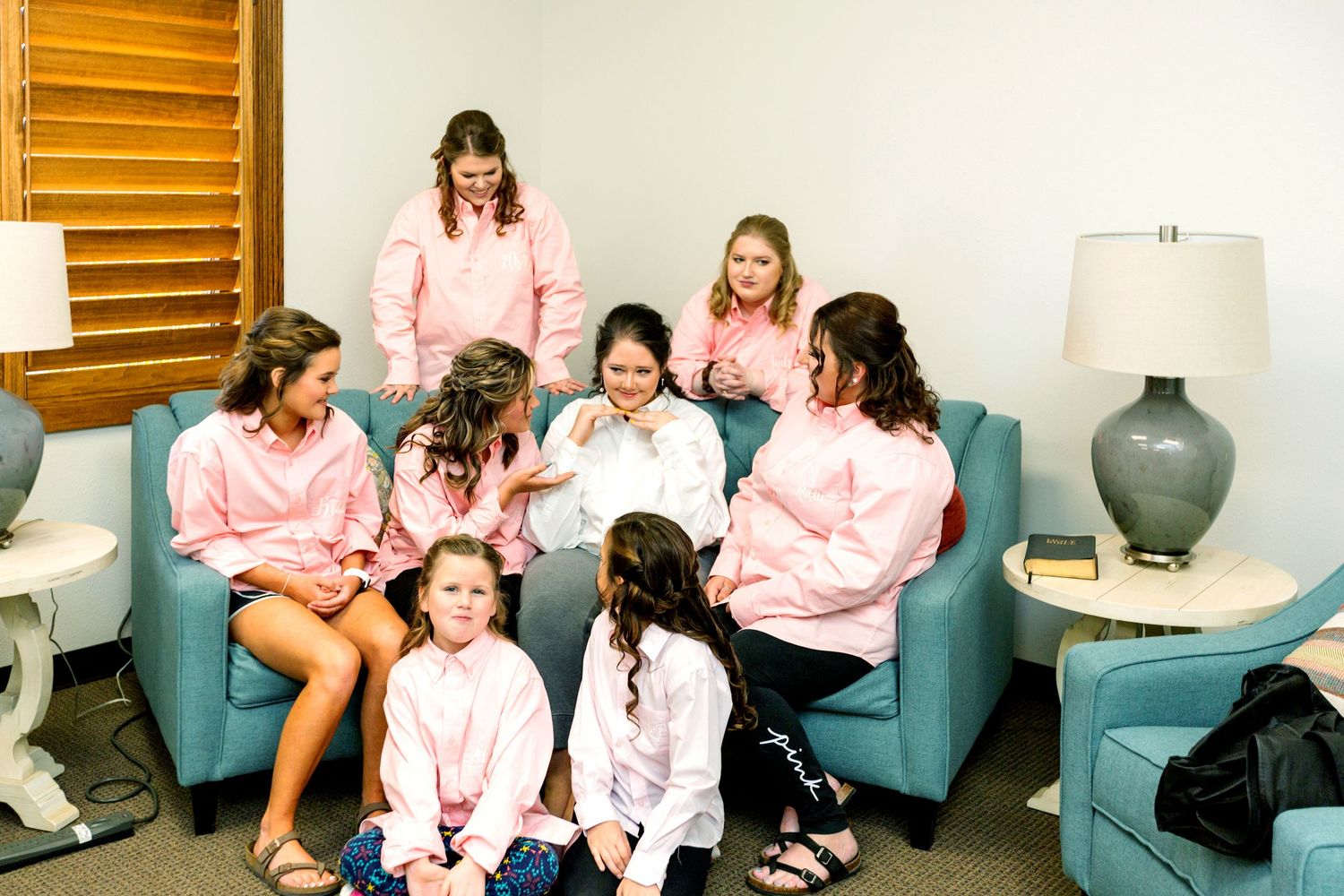 Wedding party members relaxing on a teal couch during pre-ceremony preparations.