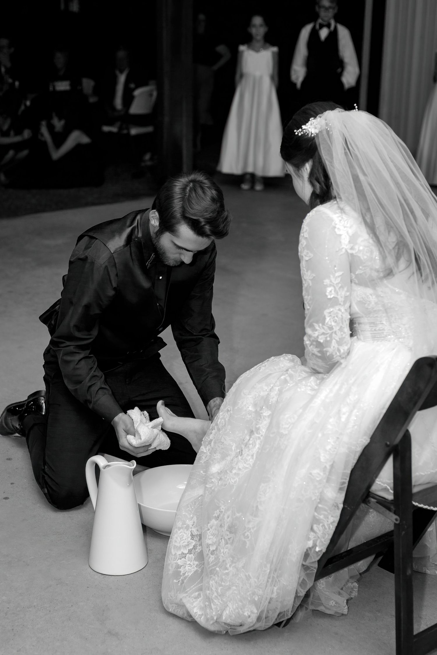 Black and white wedding reception moment during traditional foot washing ceremony.