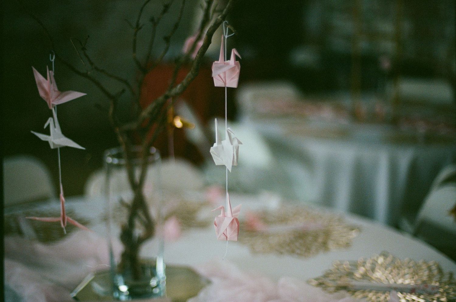 Wedding reception decor with hanging paper cranes and delicate lighting details.