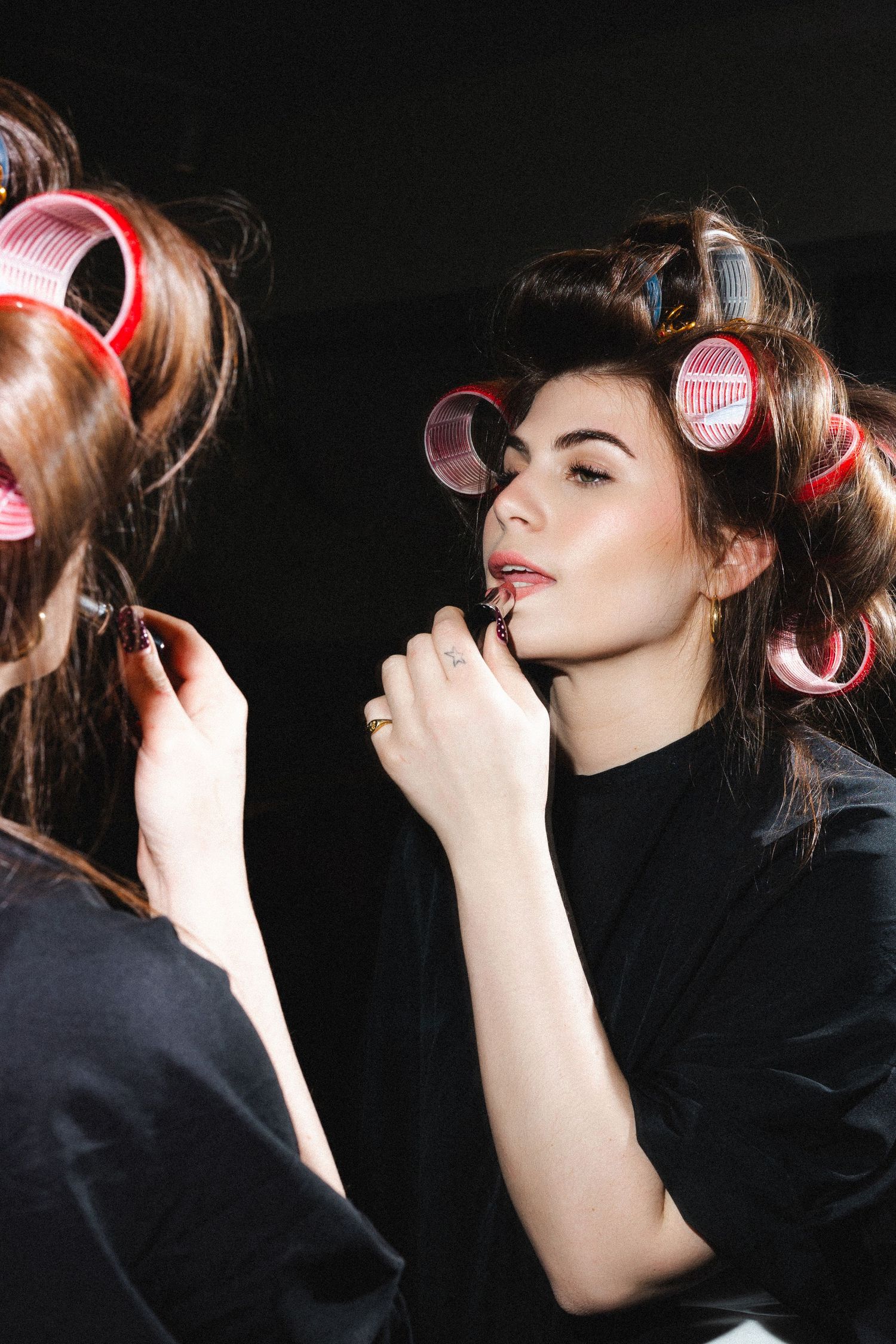 Hair styling sequence showing pink rollers being applied in dark setting.