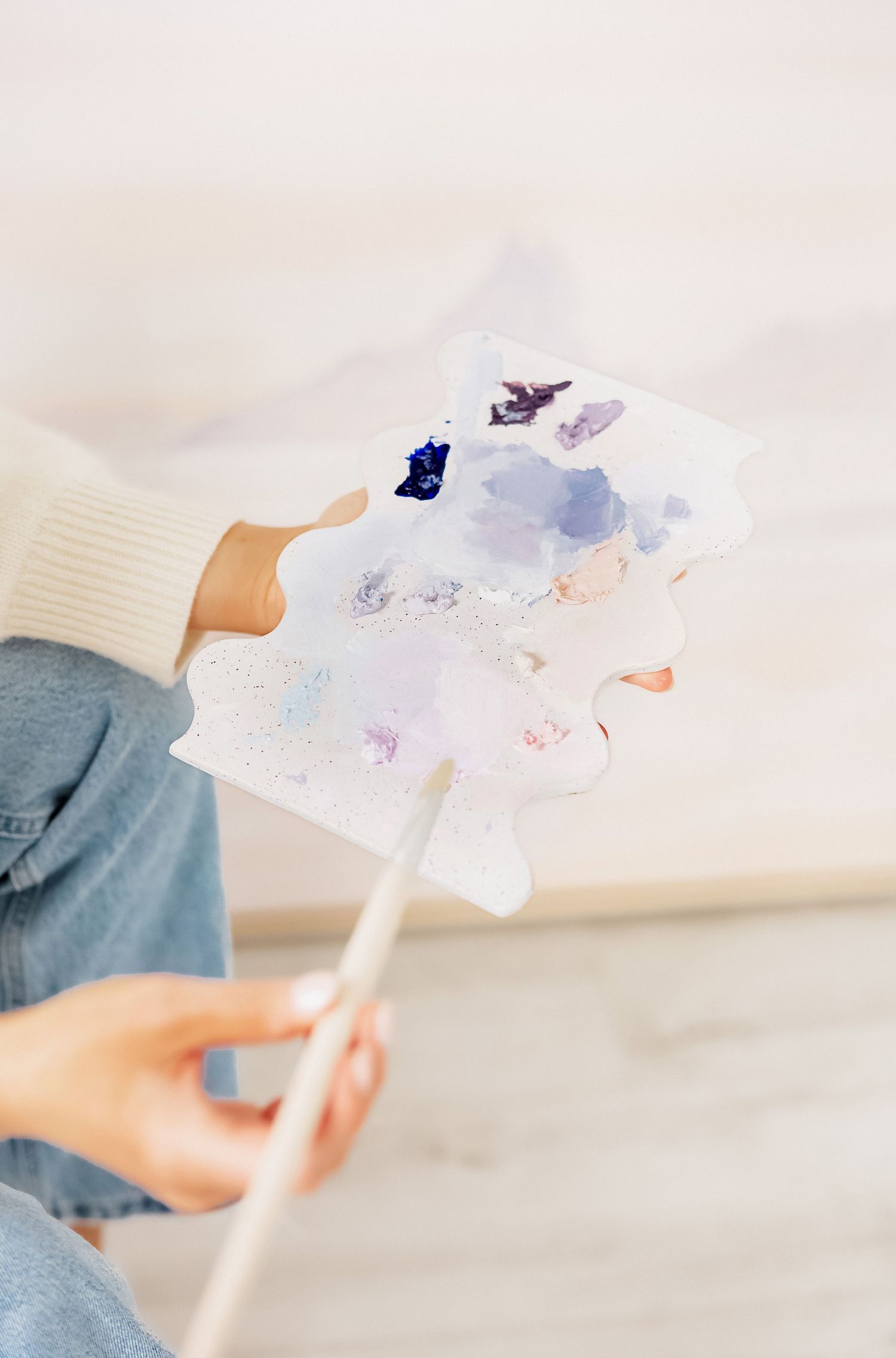 Close up of hands holding watercolor painting with blue and purple tones.