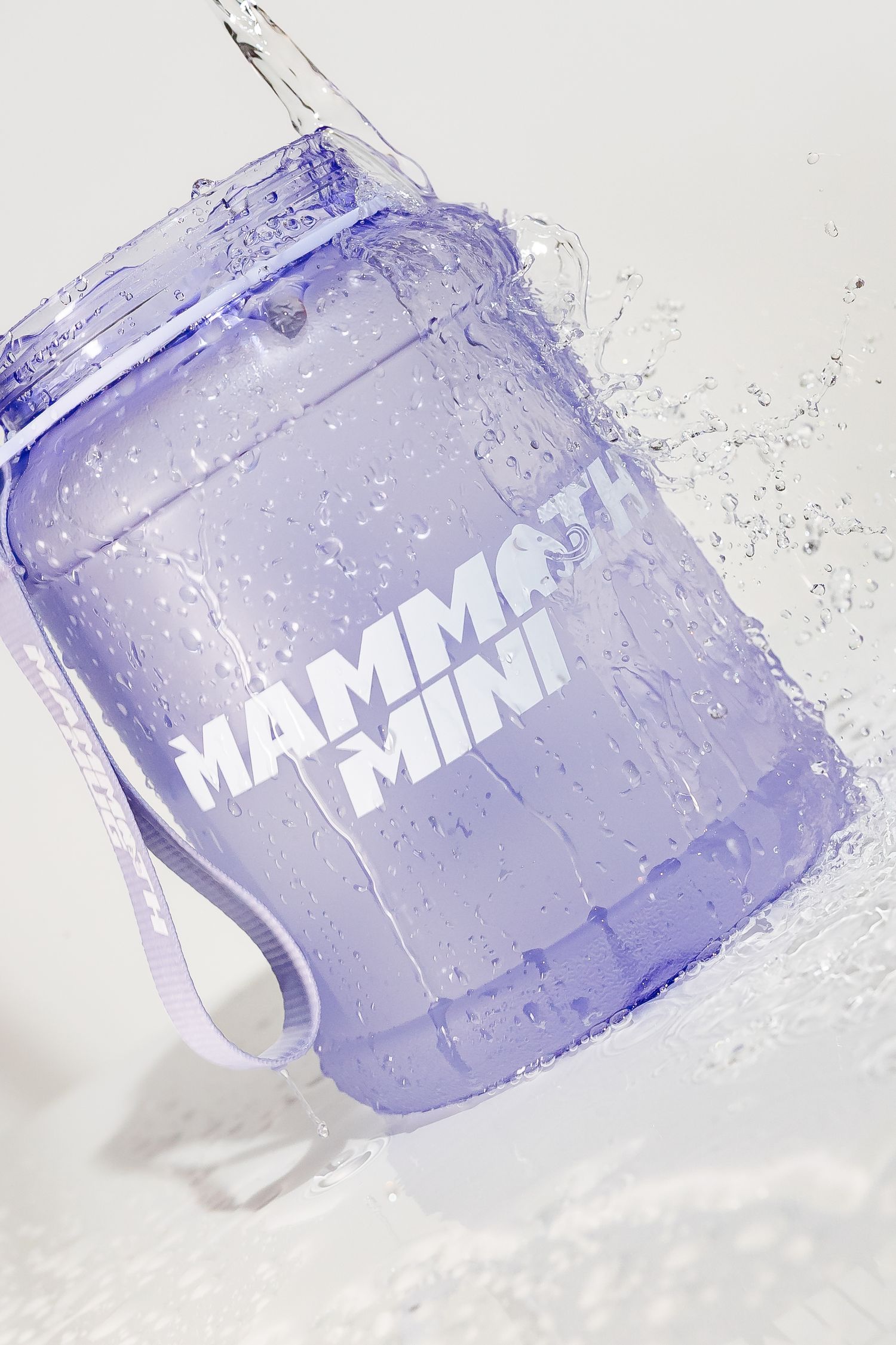 Wet purple Mammoth Mini shaker bottle with splashing water effect in studio lighting.
