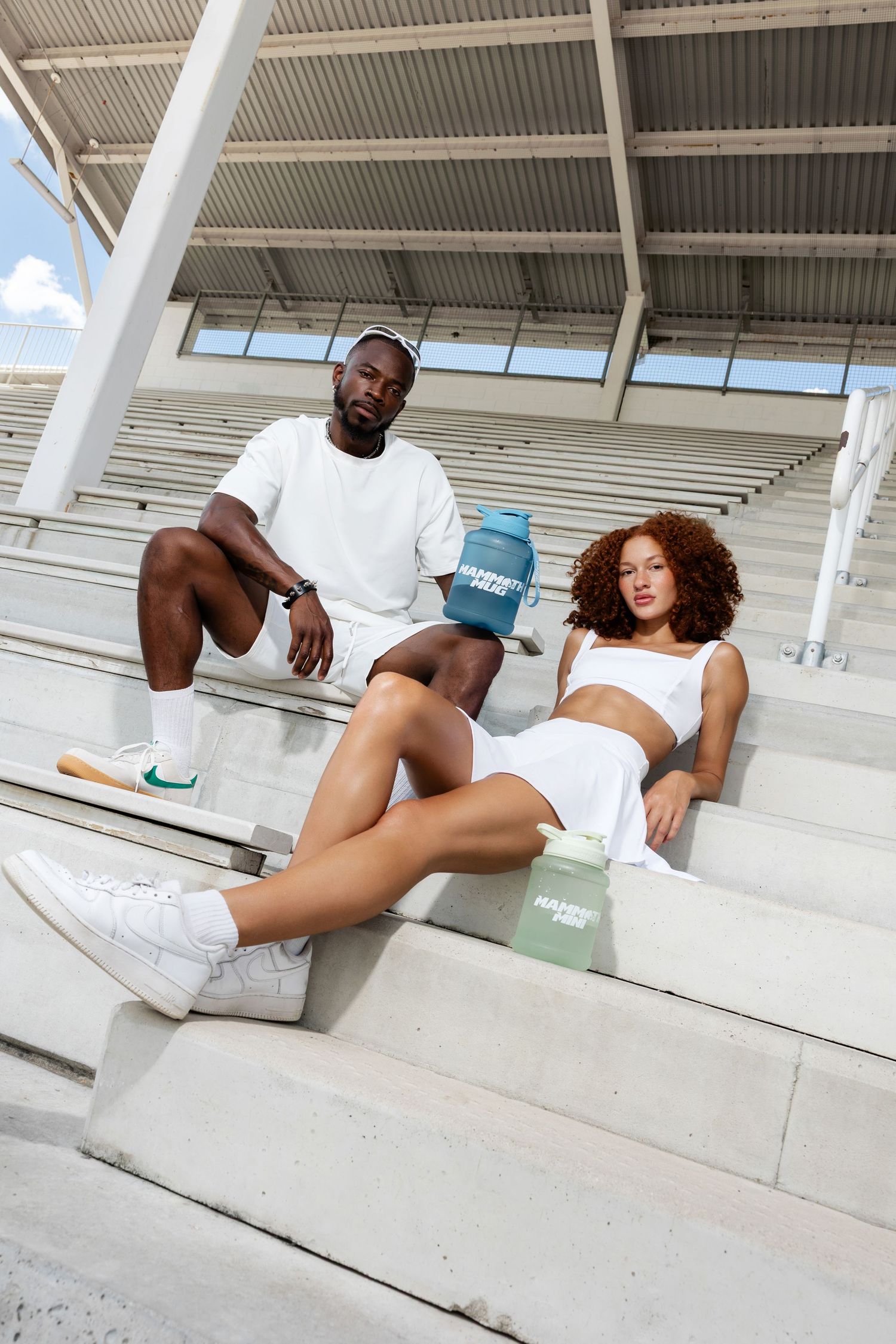 Casual lifestyle photo on concrete stadium seating with water bottles and athletic wear.
