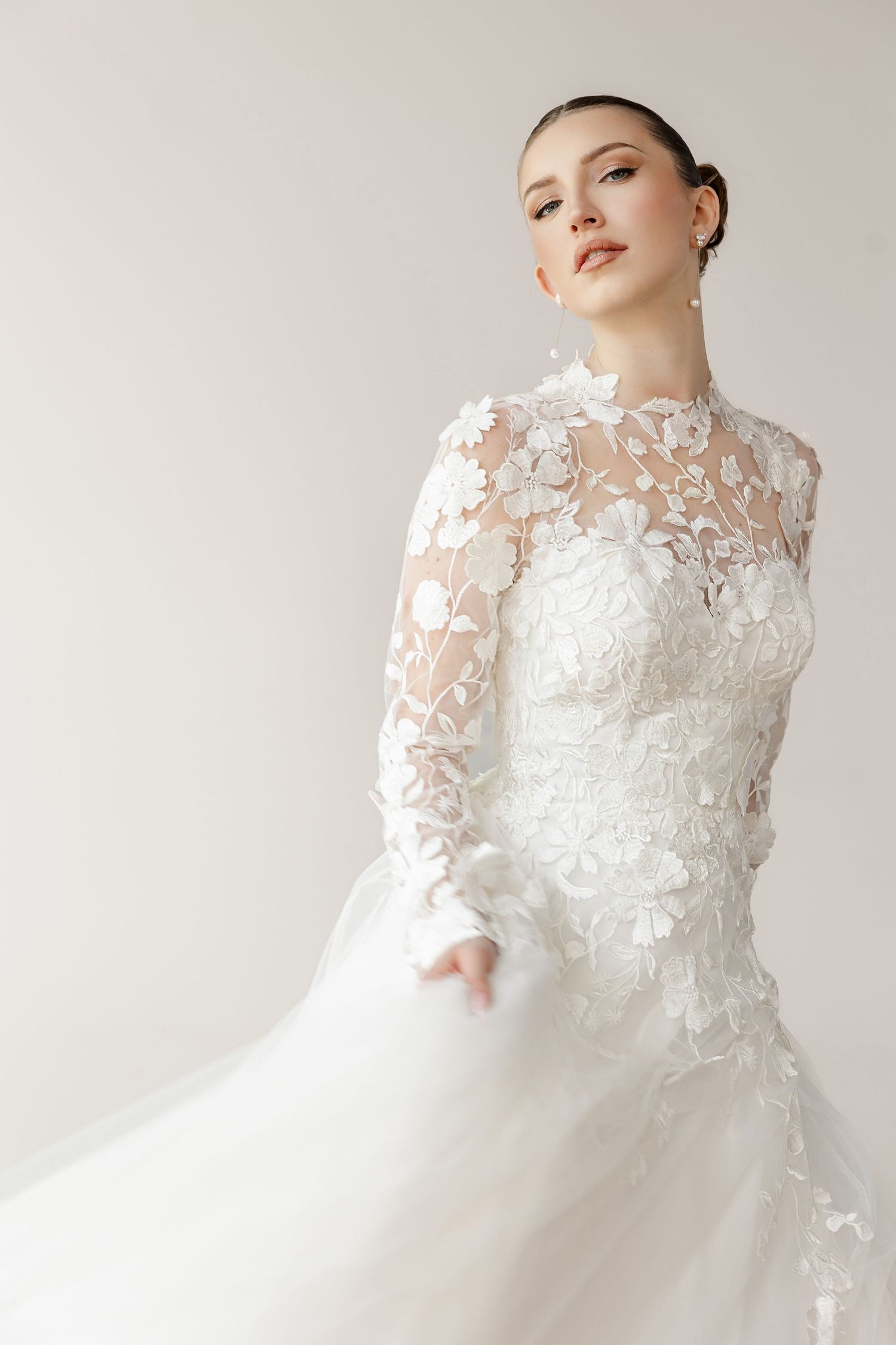 High-neck lace wedding dress with intricate appliques photographed in studio lighting.