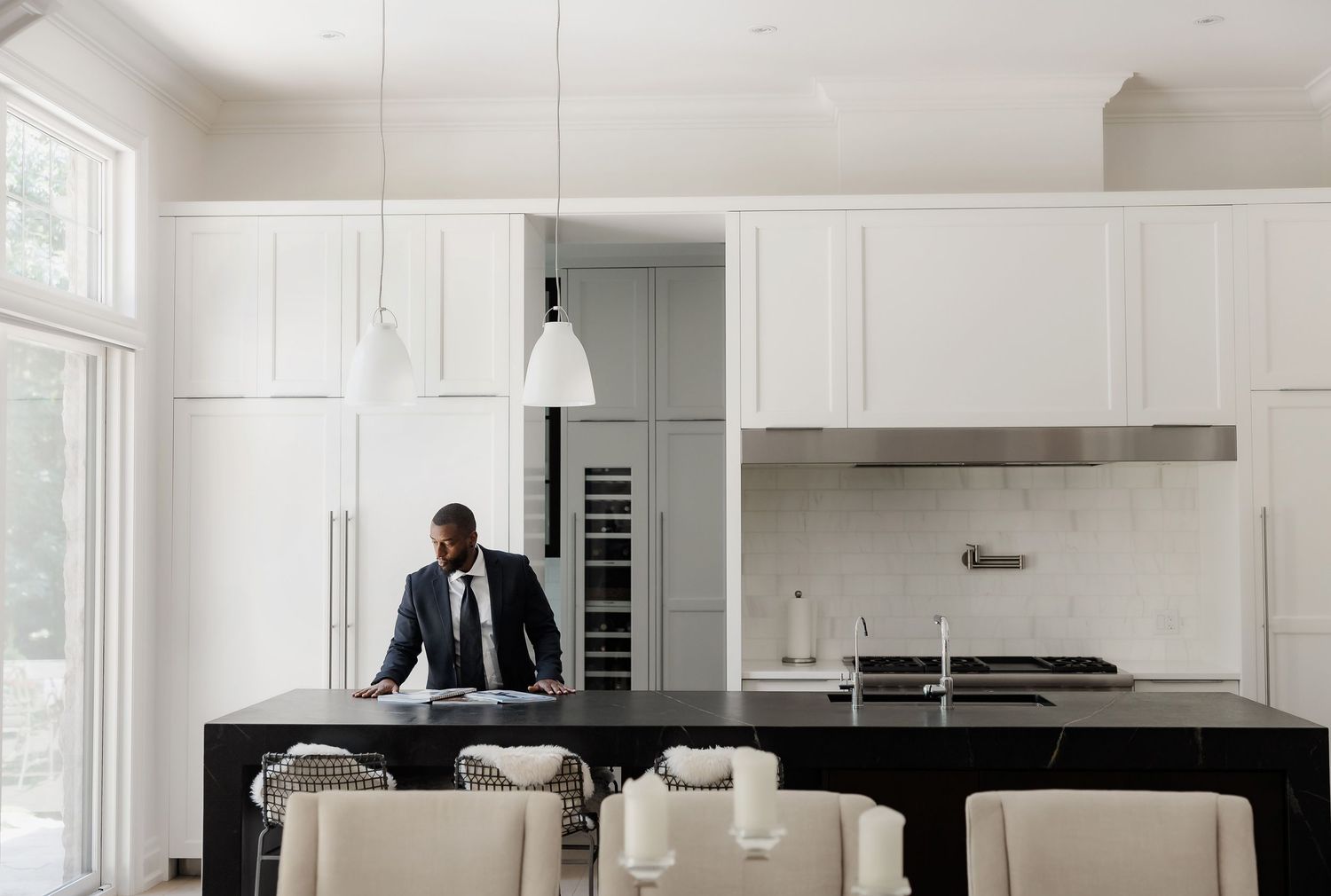 Modern white kitchen interior with black marble countertops and stainless appliances.