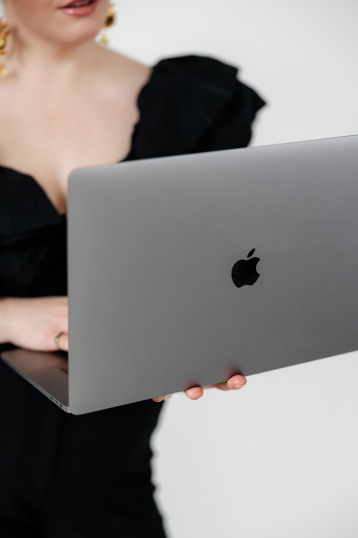 Close-up of MacBook laptop being held while wearing black ruffled top.