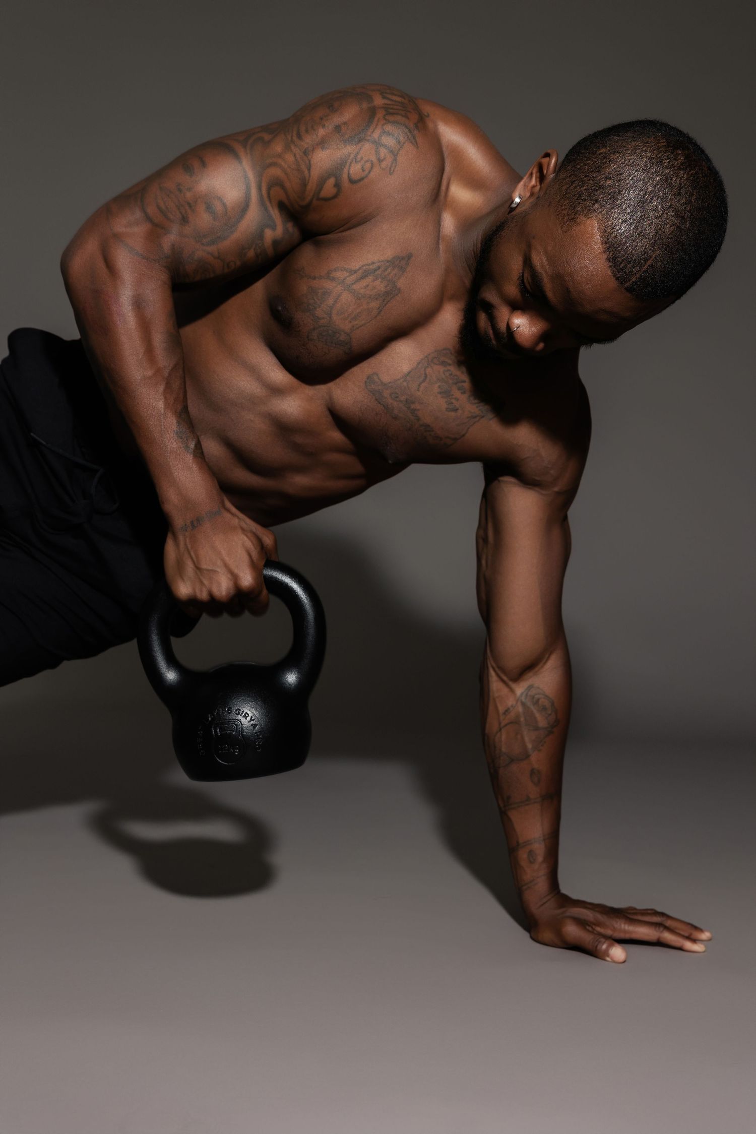 Strong athlete demonstrating proper kettlebell pushup form in studio.