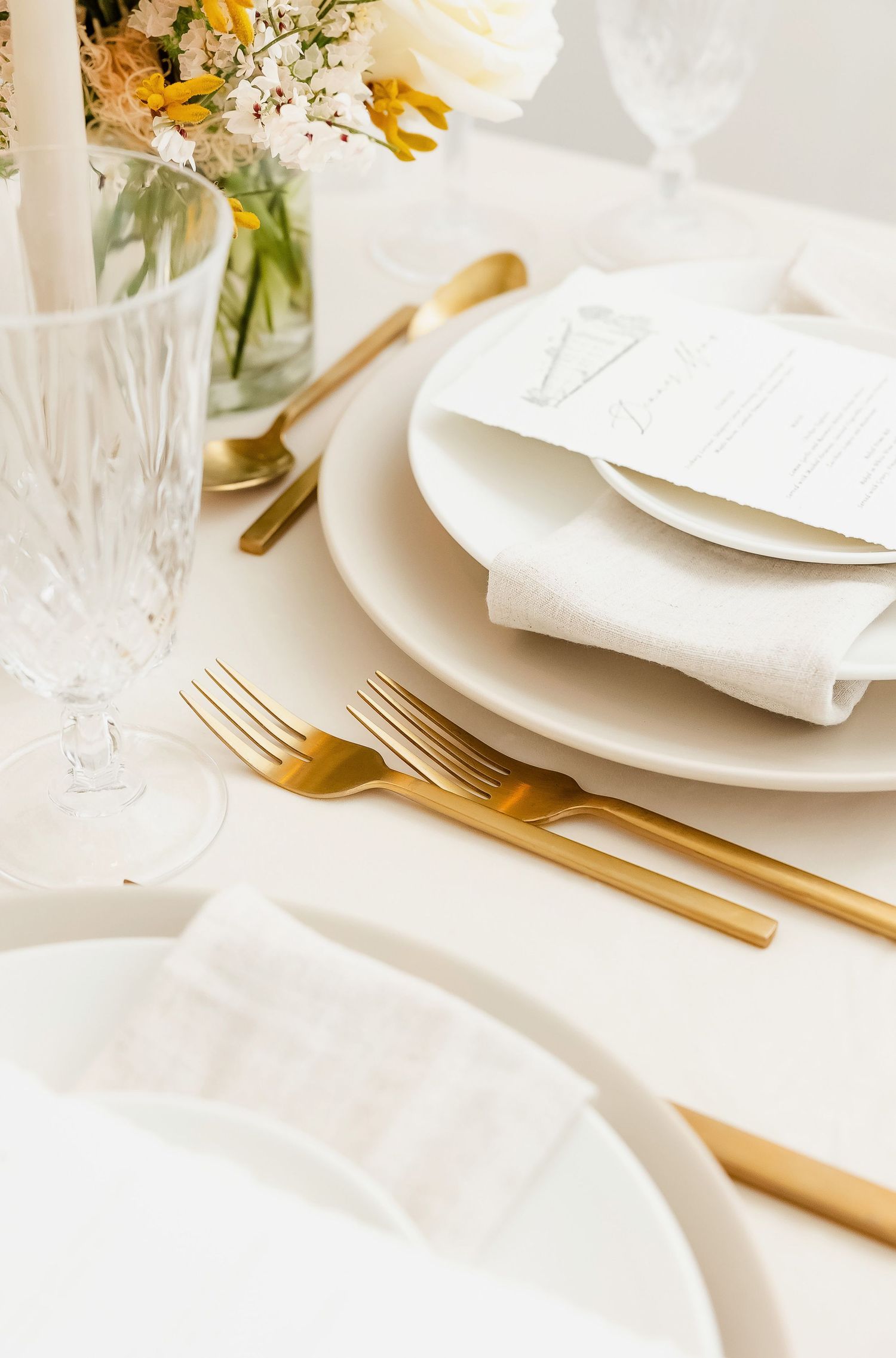 Close-up of elegant table setting with crystal glassware and gold cutlery.