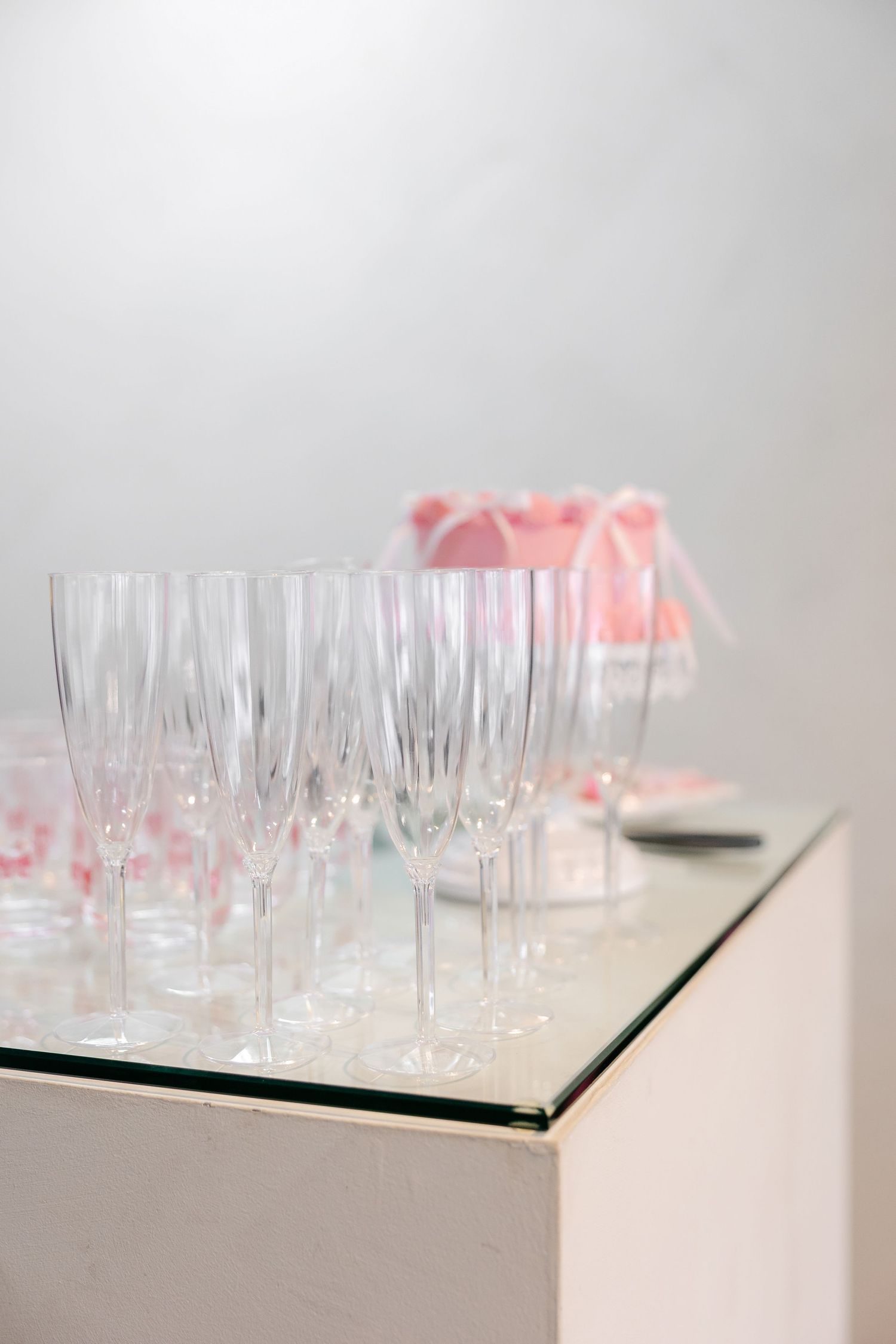 Array of champagne glasses arranged on white surface with pink accents.