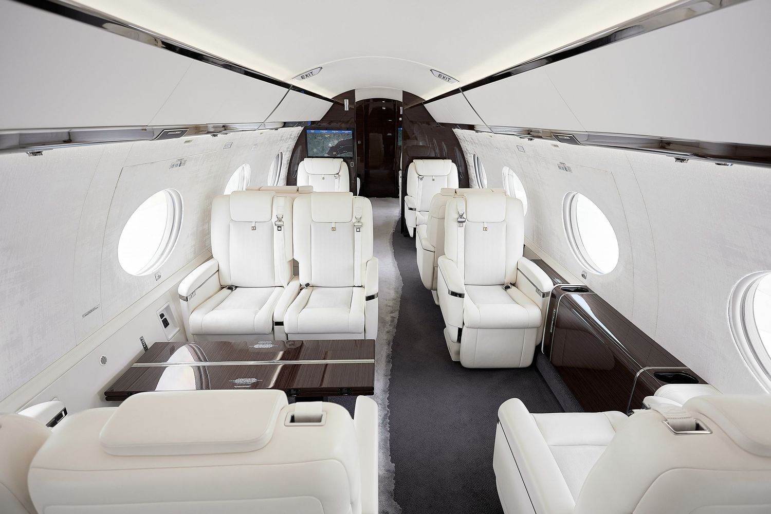 Interior view of a luxury private jet cabin with white leather seats and wood paneling.