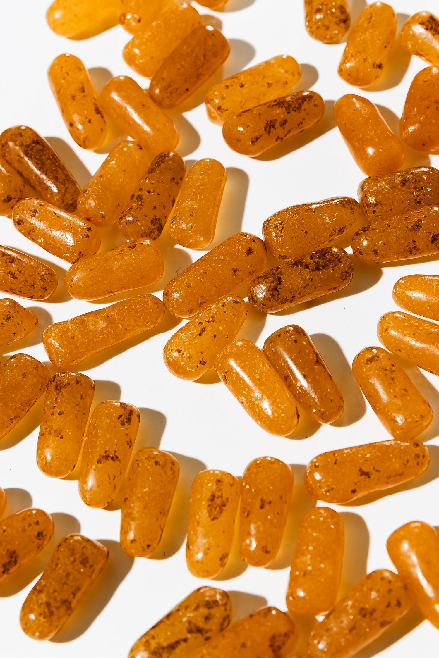 Orange Mike and Ike candies scattered on white surface with dramatic lighting.