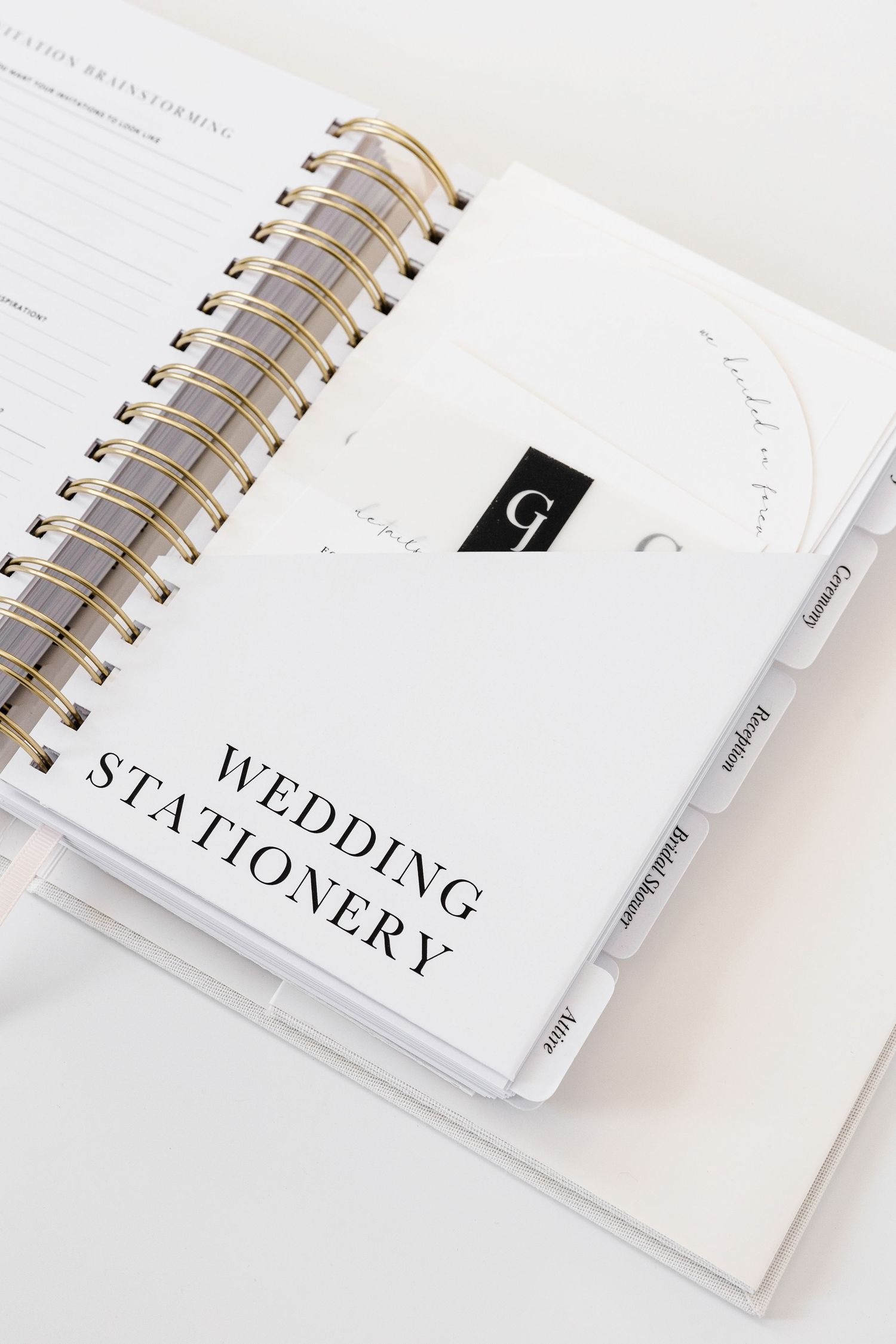 White spiral-bound wedding stationery notebooks with minimalist text design against light background.