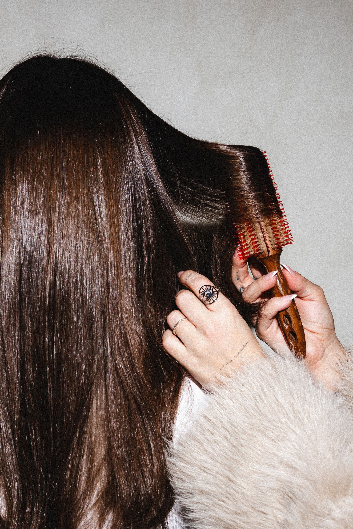 Hair styling sequence showing brush techniques with white furry background.