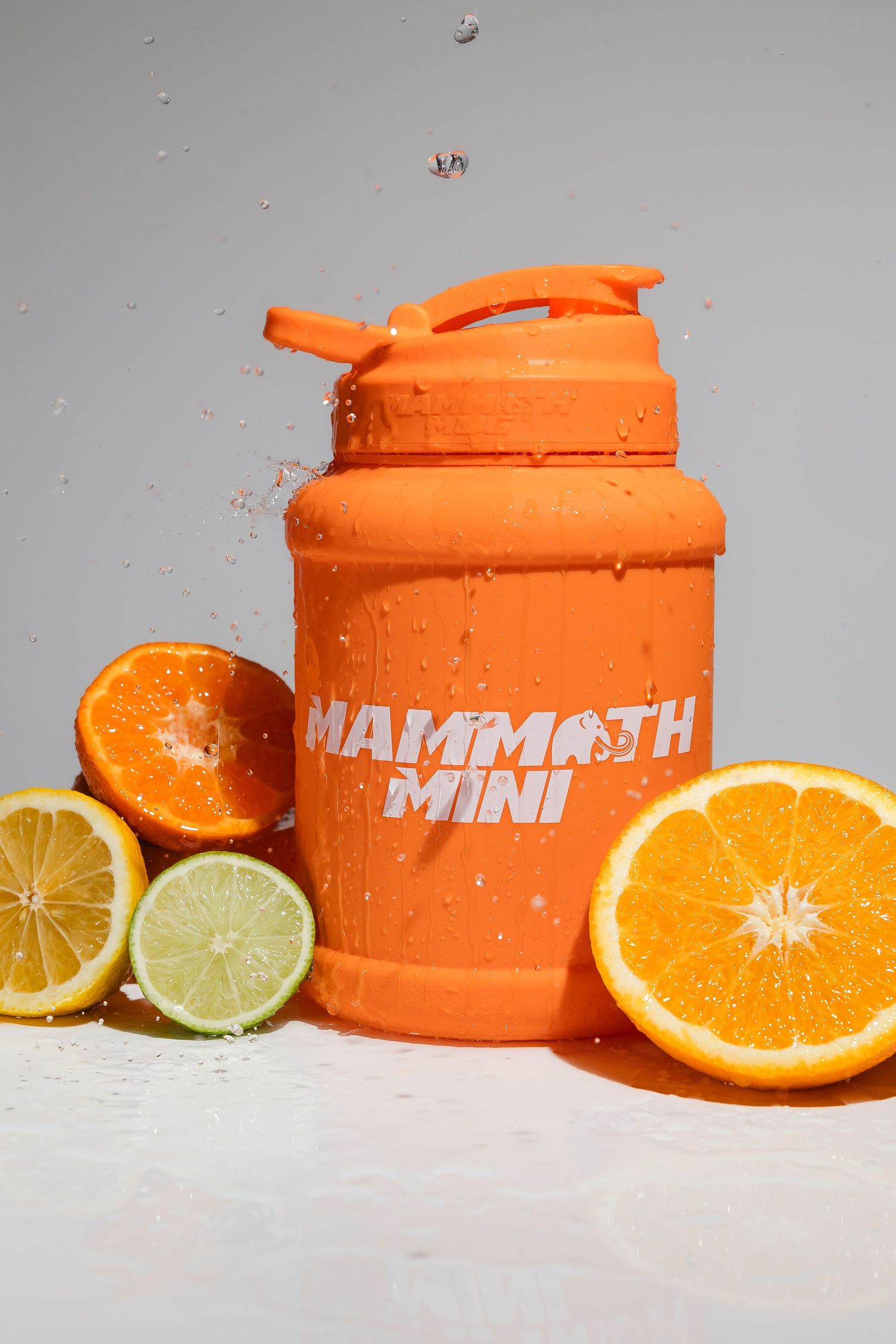 Orange Mammoth Mini shaker bottle displayed with fresh citrus fruit slices.