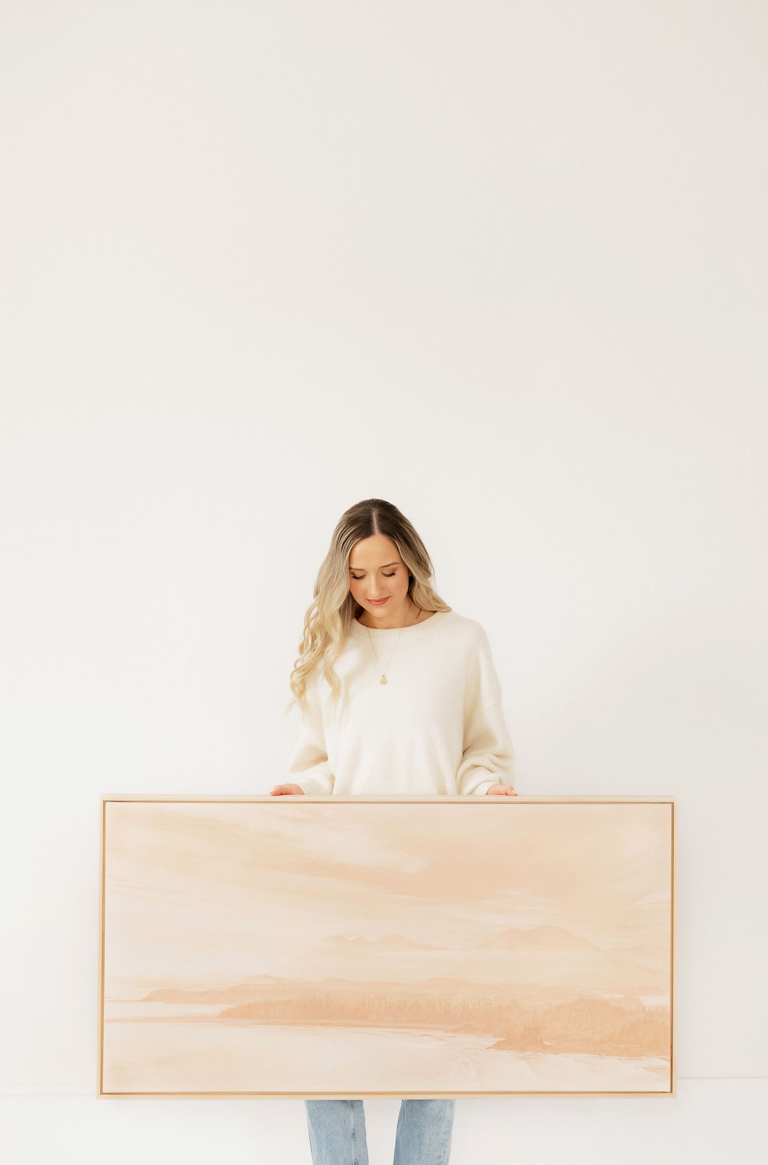 Minimal aesthetic product photography showing a person holding a light peach colored frame against white background.