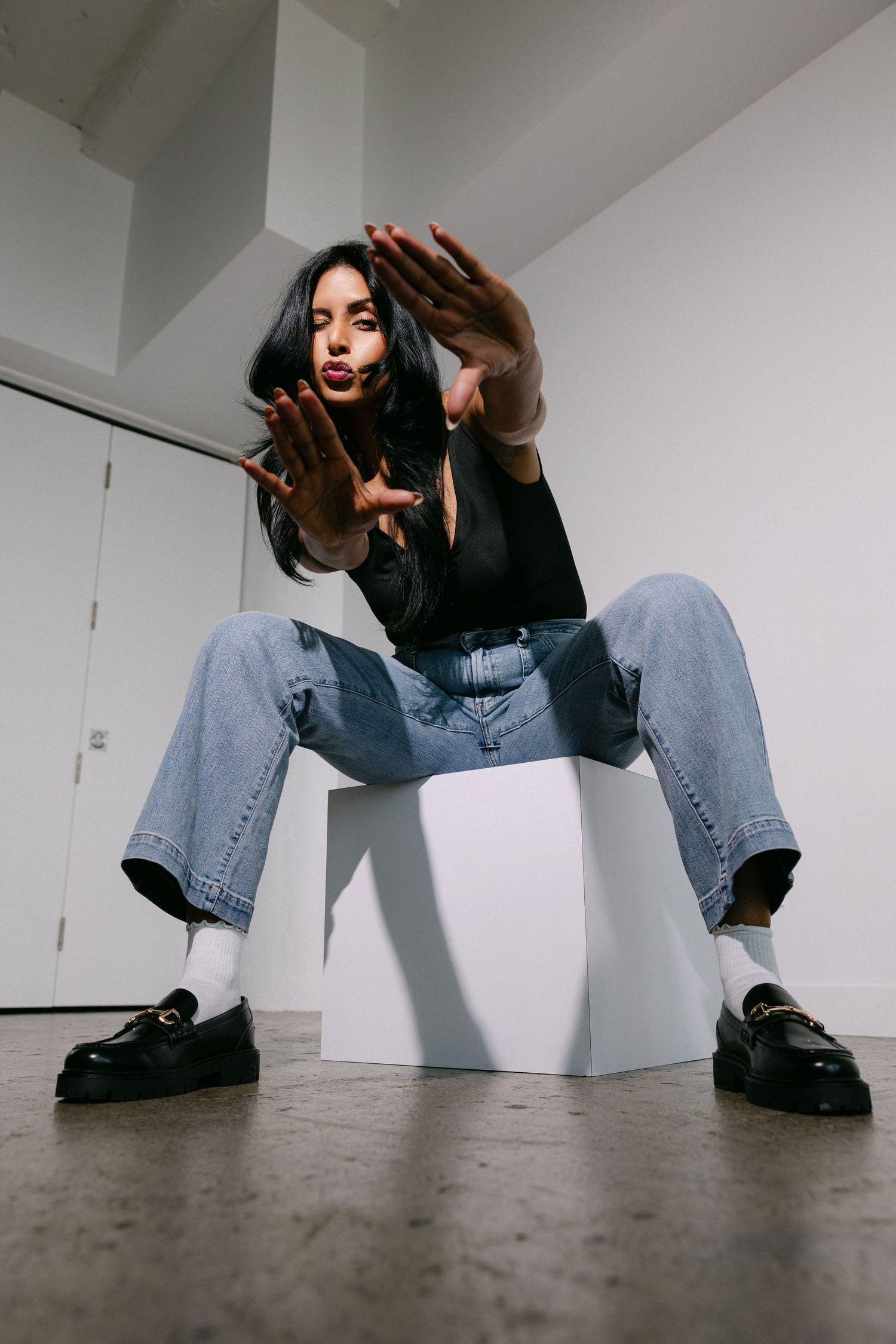 Creative ground-level fashion poses against white walls showing urban streetwear style.