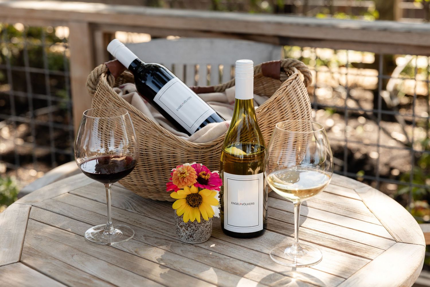 Outdoor wine tasting setup with glasses and bottles on wooden table.