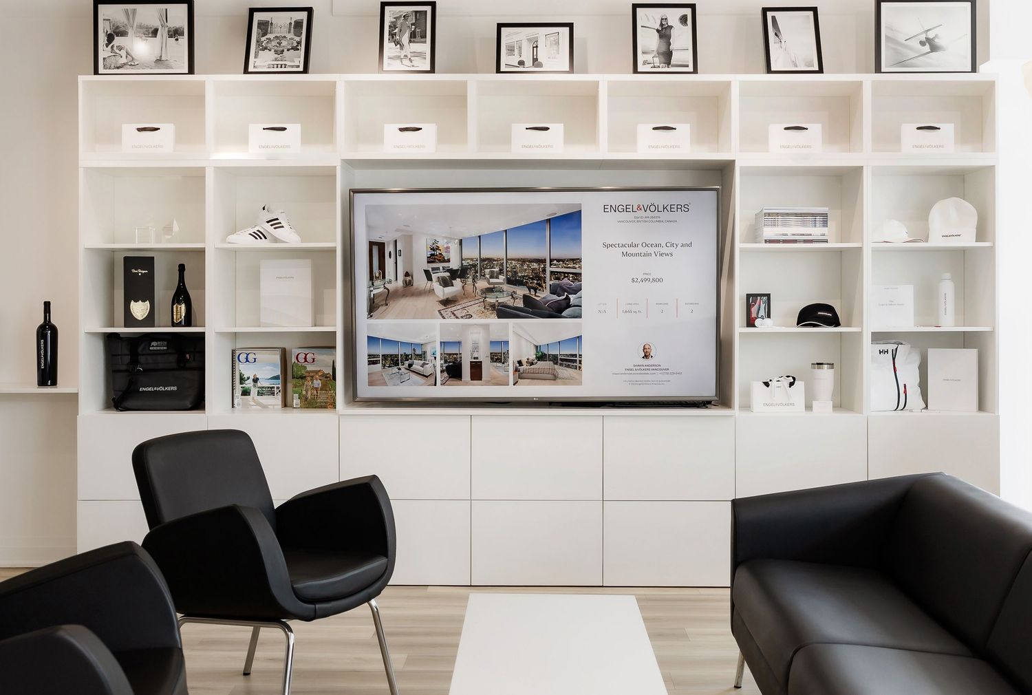 Minimalist office interior with white built-in shelving and black furniture.