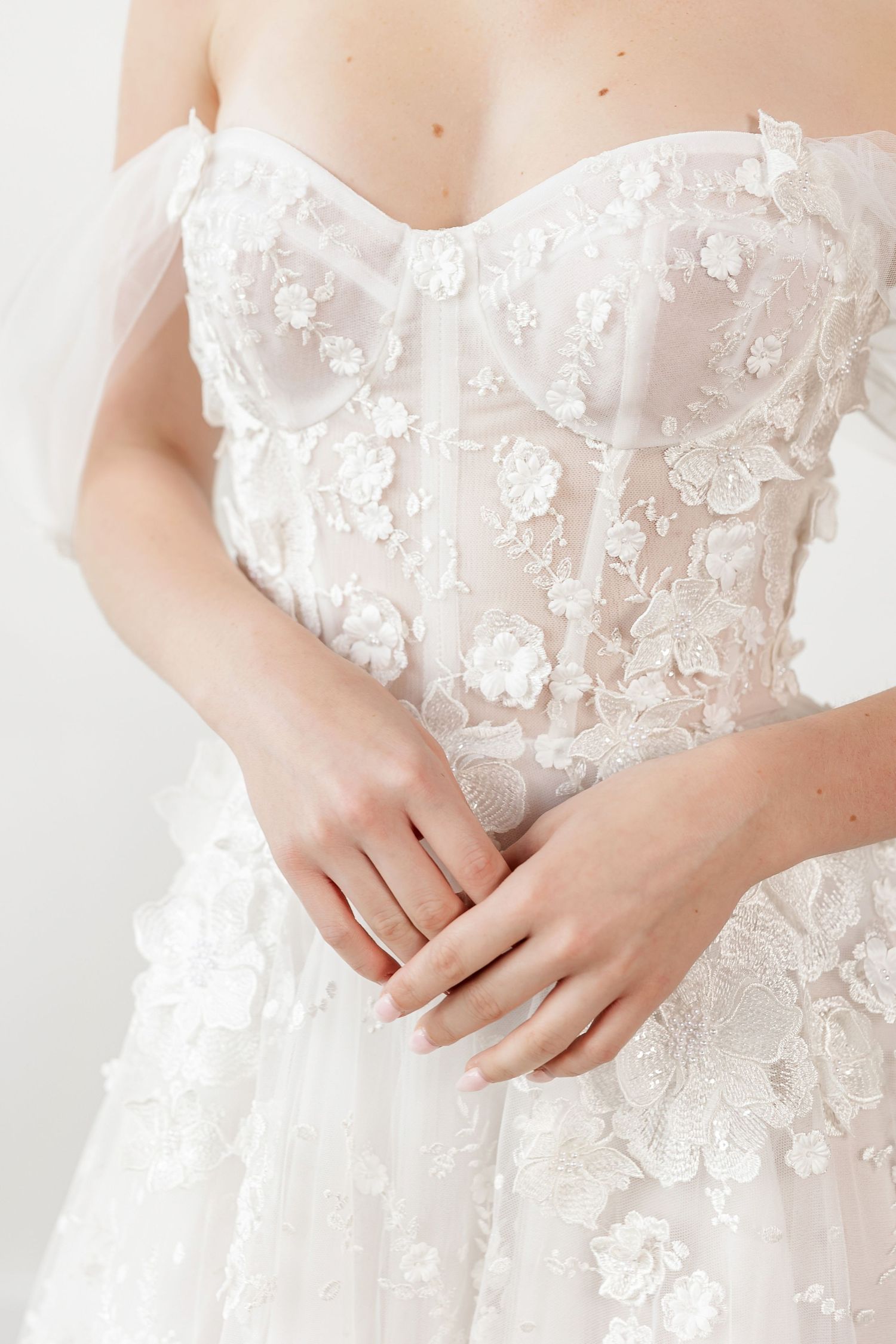 Detailed view of wedding dress bodice showing intricate floral lace and sheer fabric details.