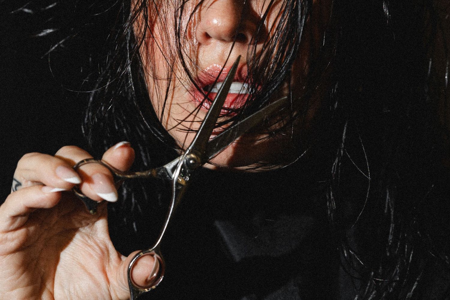 Close-up beauty portrait with dramatic lighting and dark hair against black background.