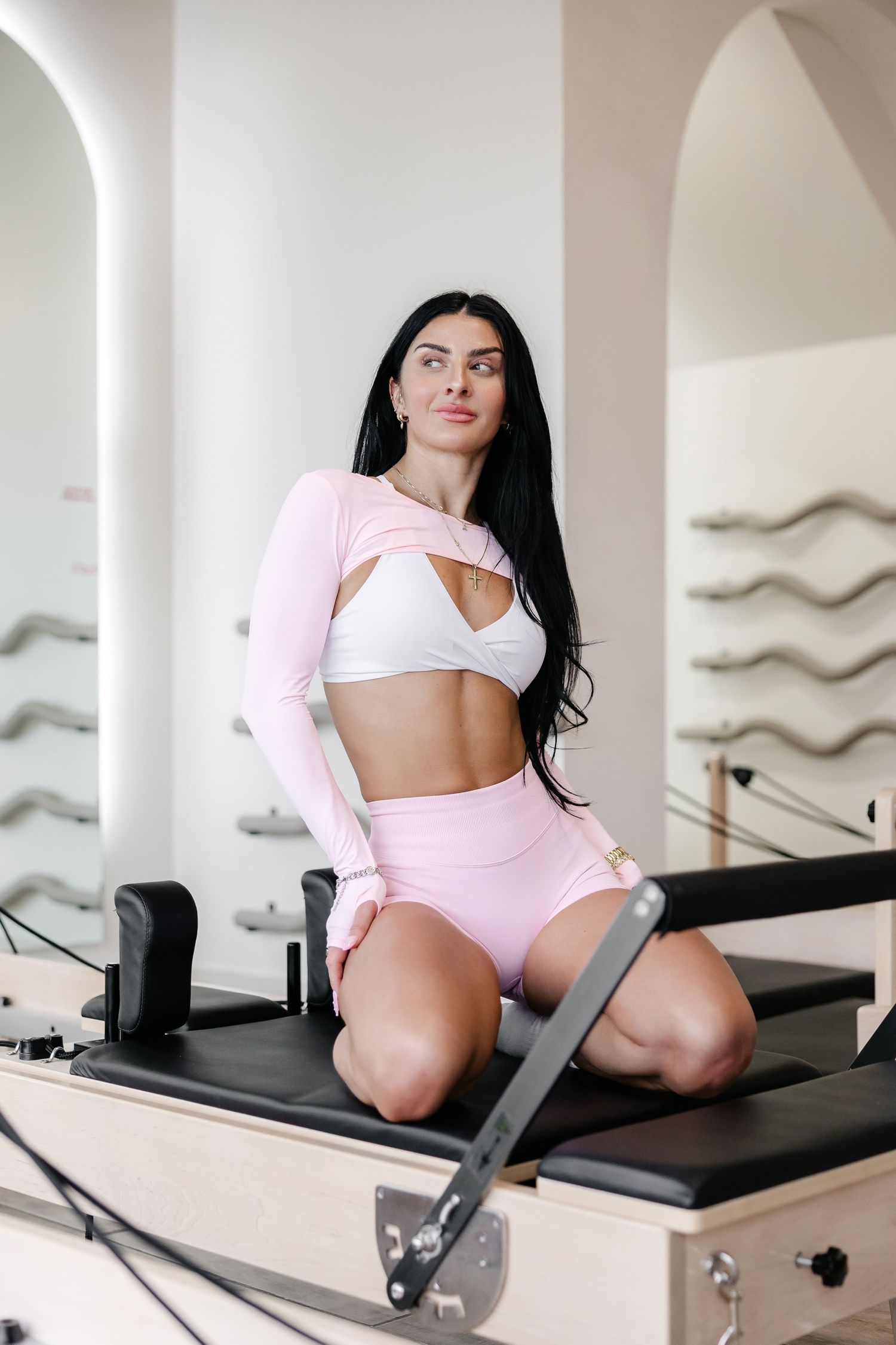 Workout session on pilates equipment in pink and white athletic wear.