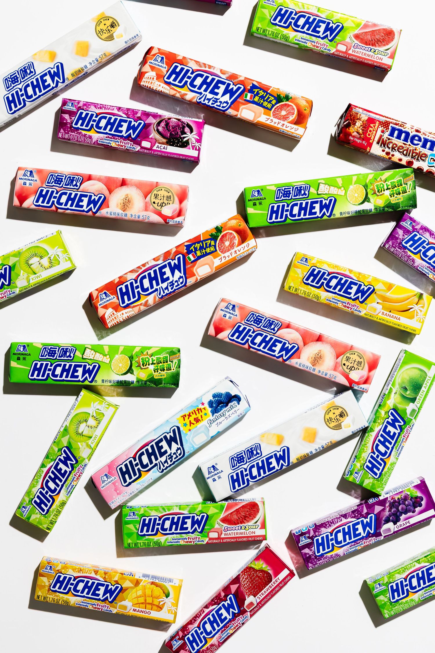 Collection of colorful Hi-Chew candy packages arranged in diagonal pattern on white background.
