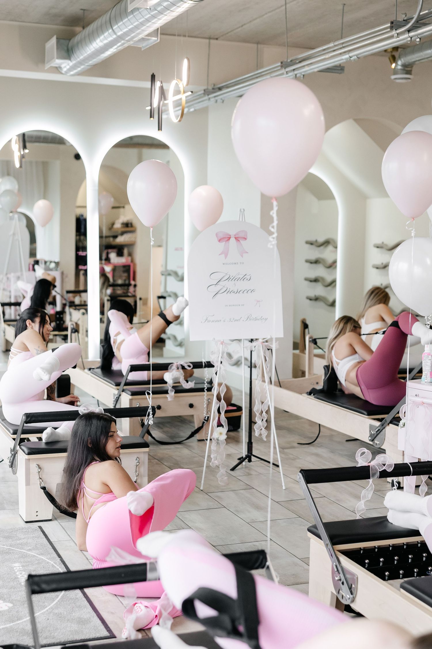 Airy fitness studio space with multiple pilates reformer machines and balloon decorations.