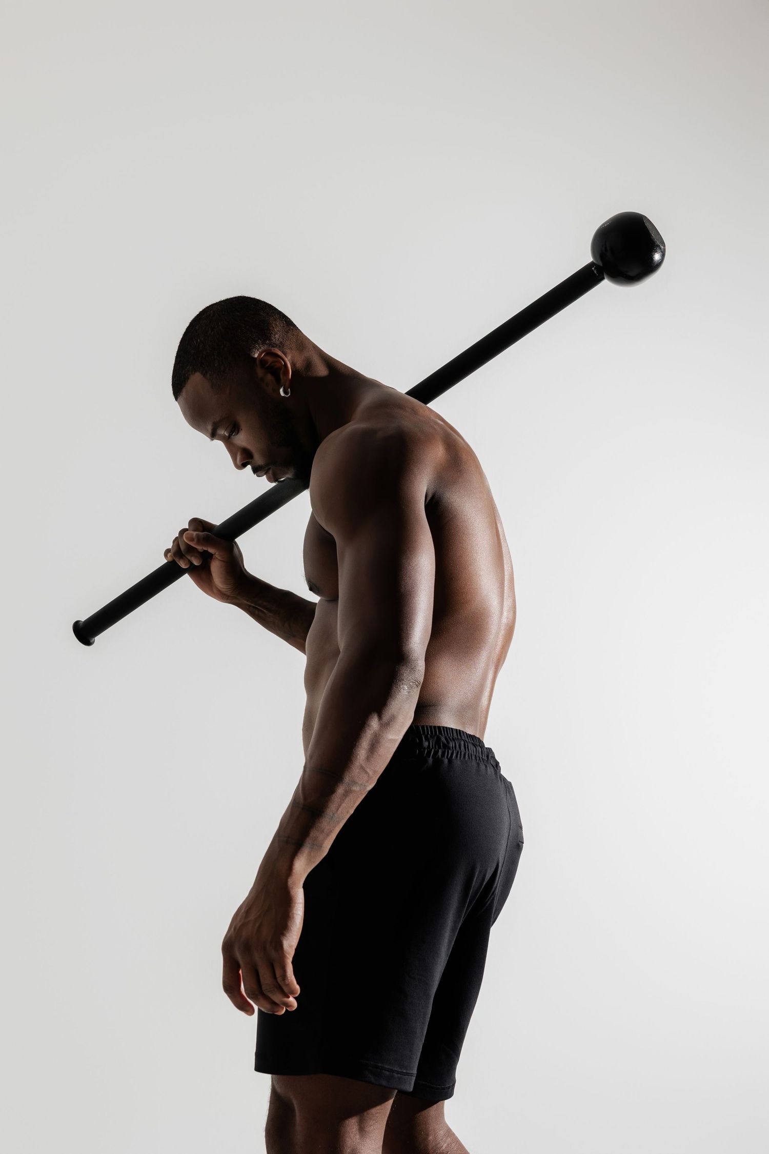 Athletic figure holding steel bar across shoulders during workout.