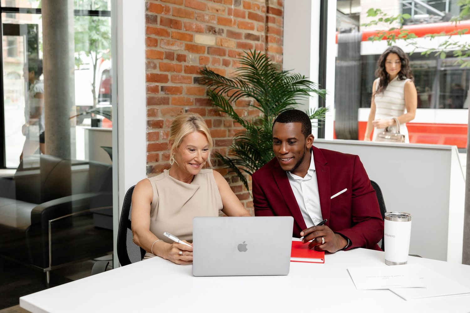 Colleagues working together at modern office with brick walls and laptops.