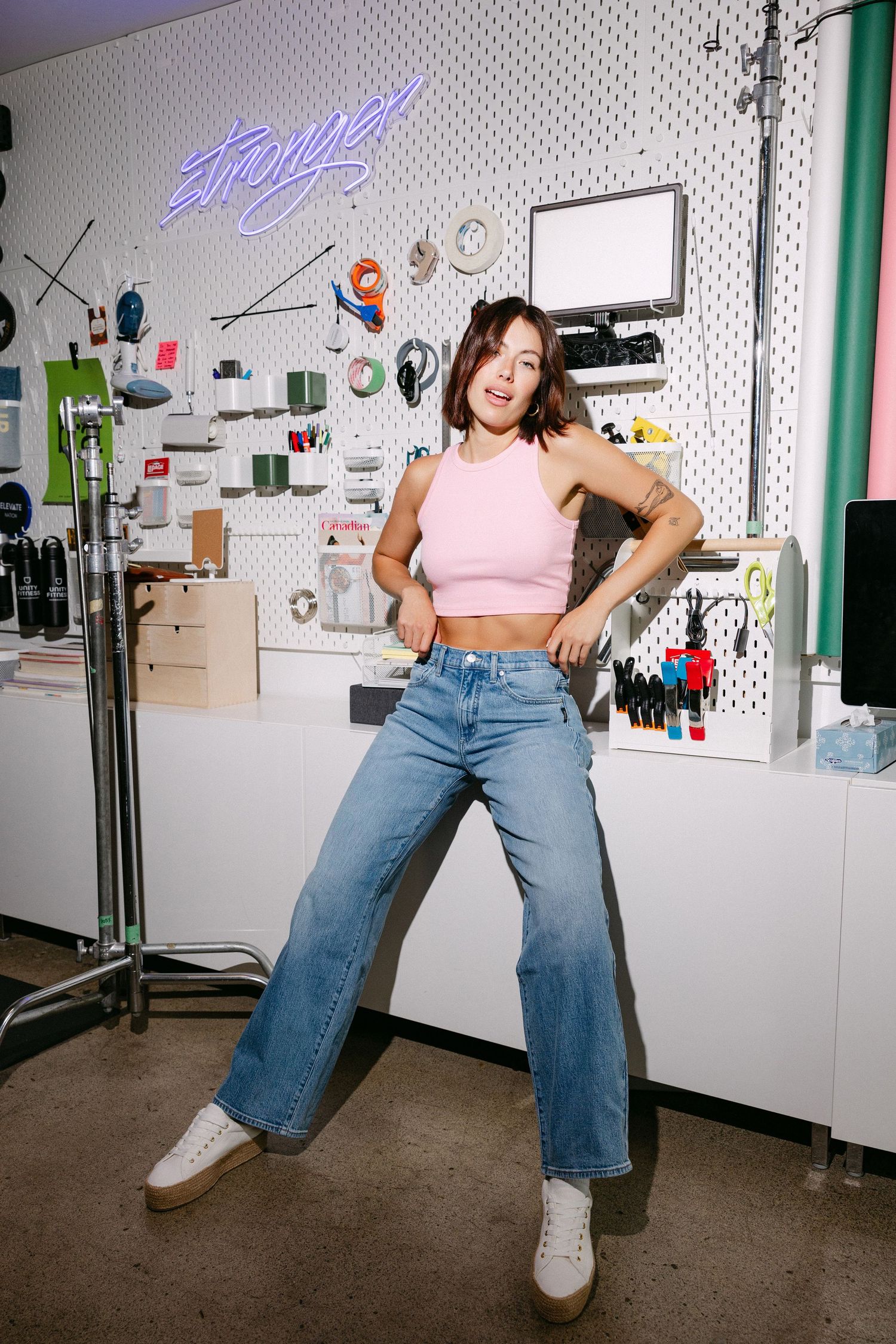 Dancing pose in front of white pegboard wall with storage solutions.