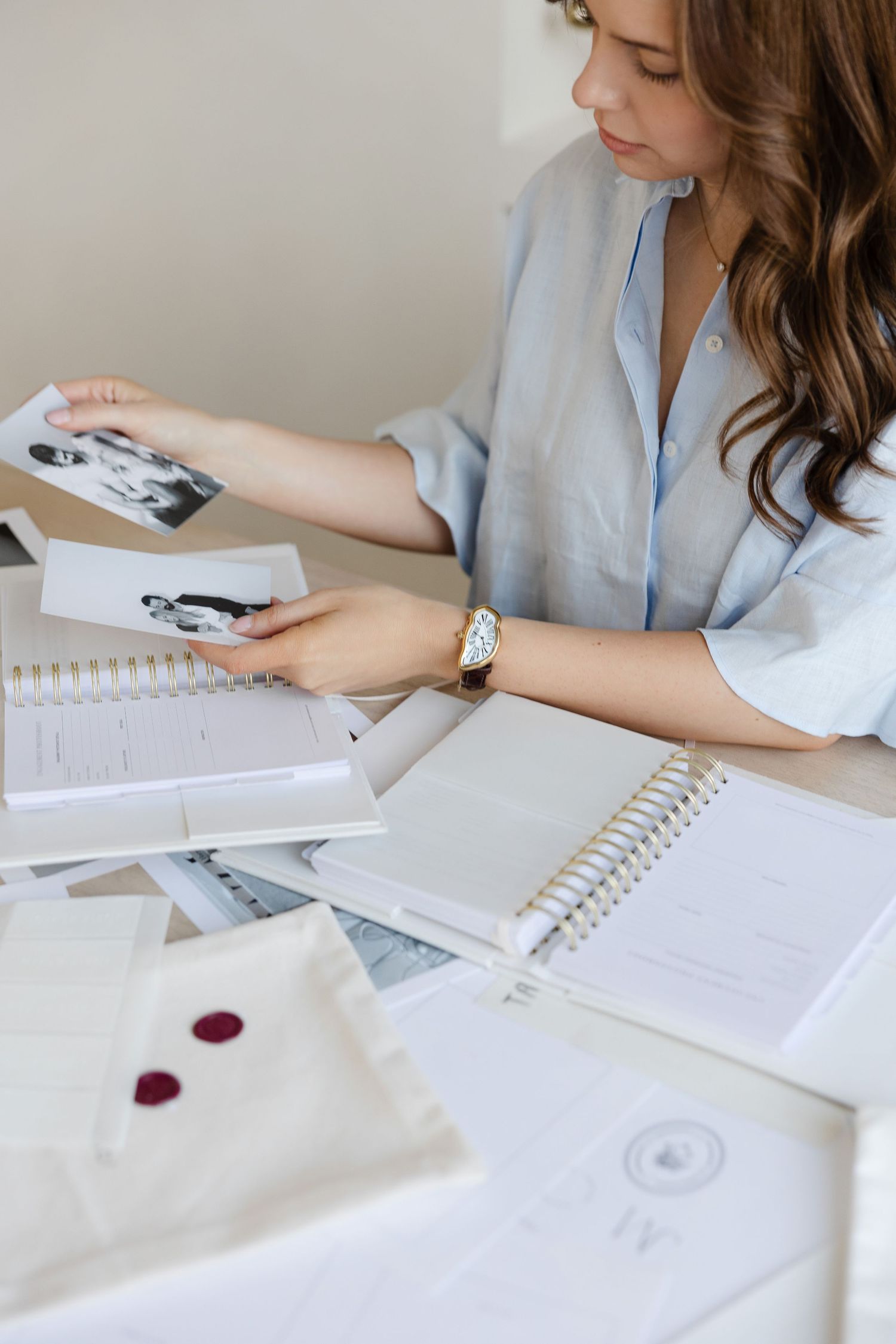Designer reviewing photographs and notebooks at organized desk workspace.