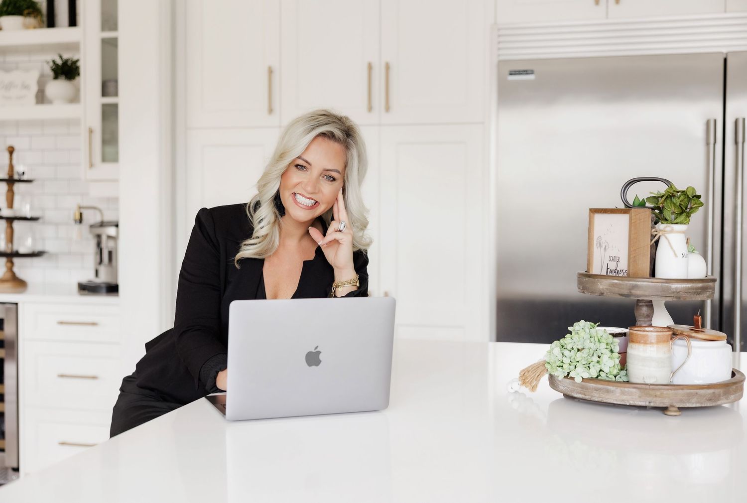 Professional working on a MacBook laptop in a bright modern white kitchen.